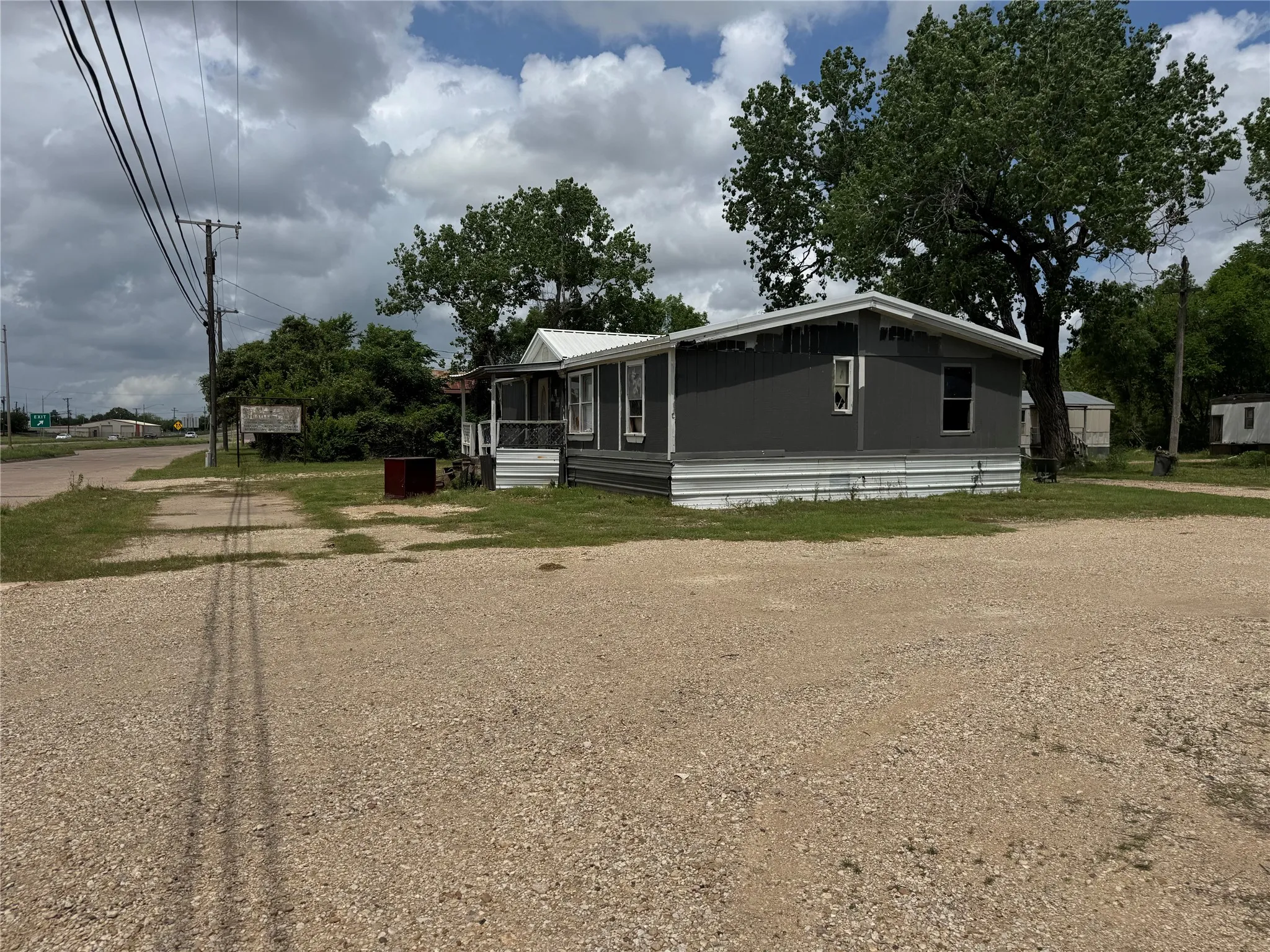 The property features a gravel lot, a gray exterior, and a white roof
