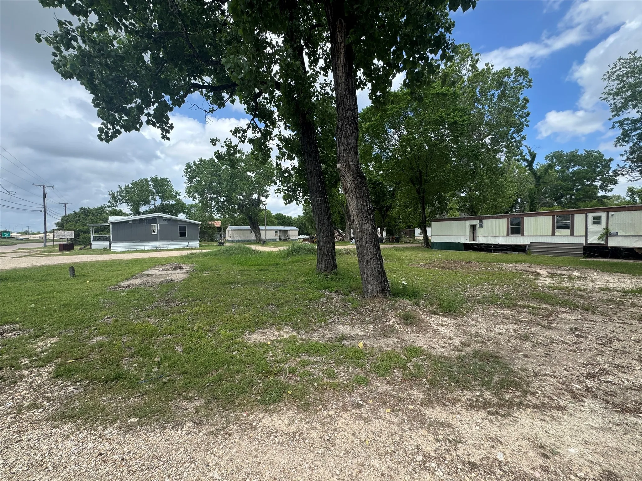 The property offers a gravel and grass area with mature trees