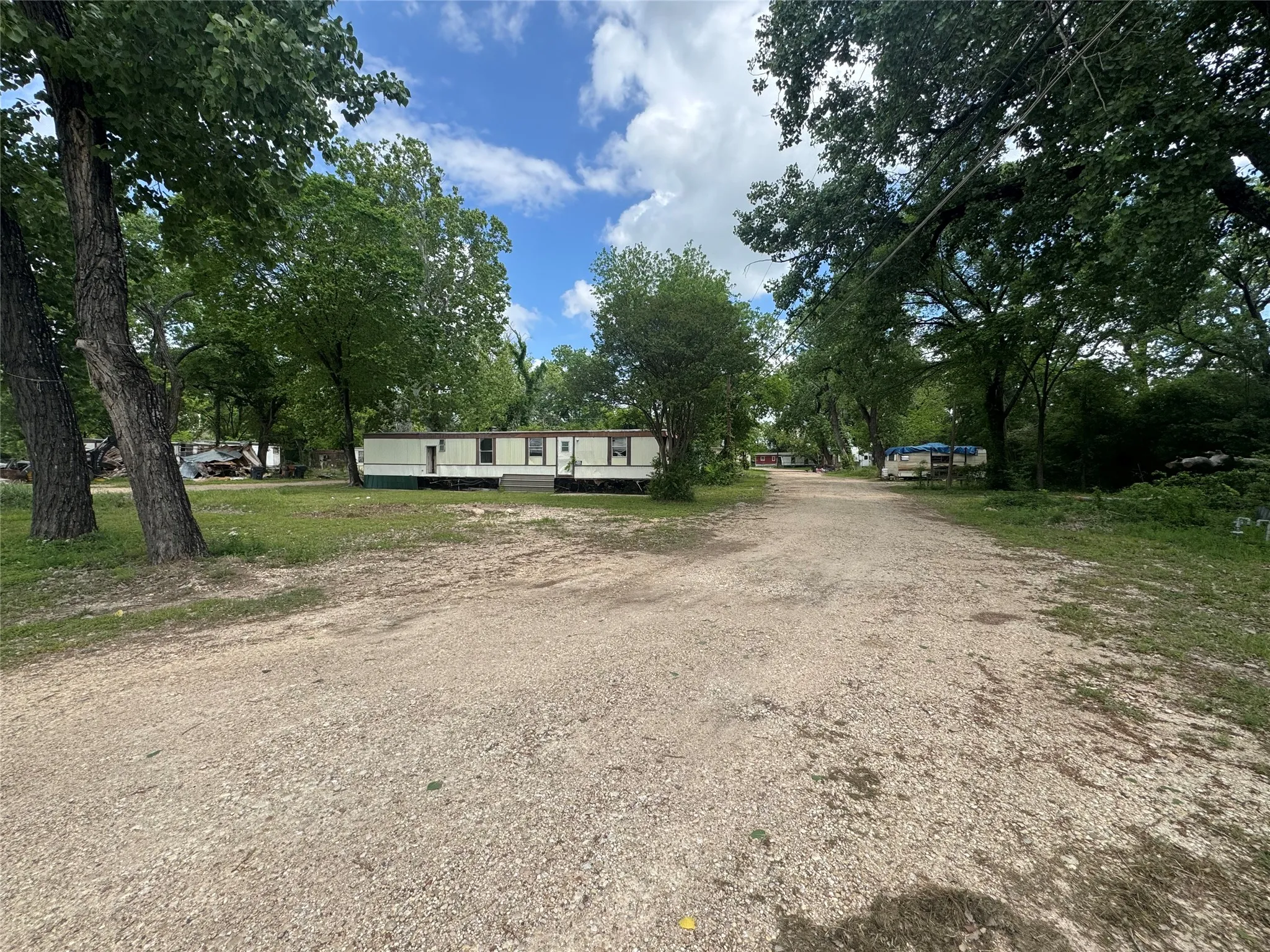 The property features a gravel driveway and surrounding mature trees