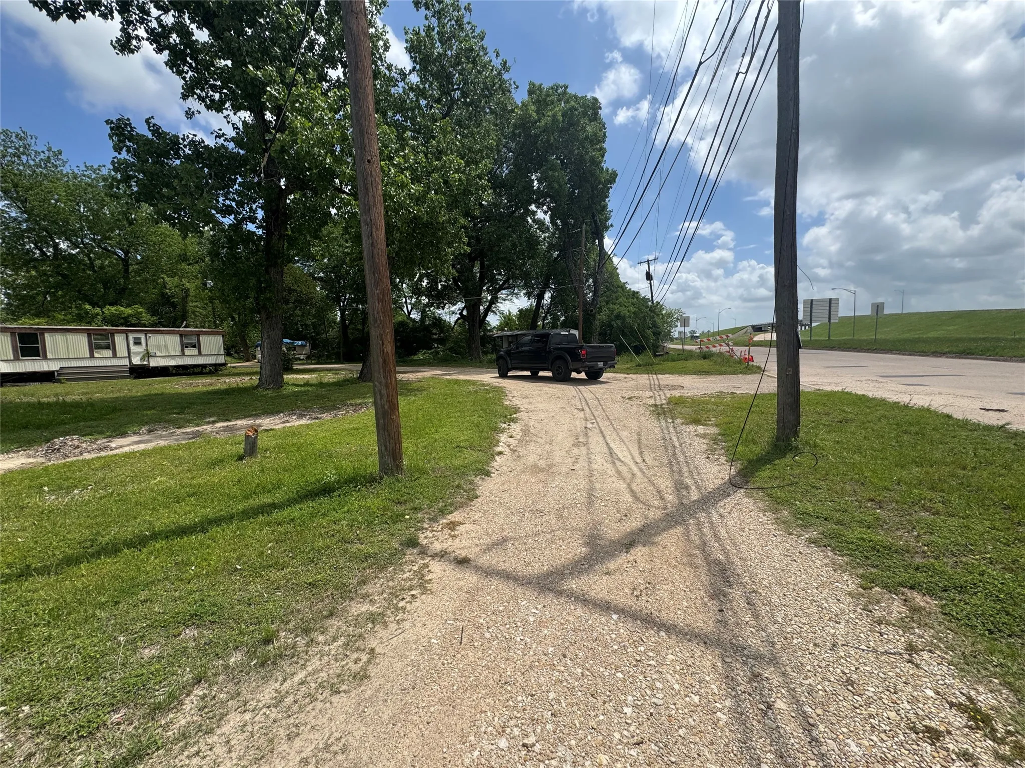 The property features a gravel driveway and a grassy area with trees