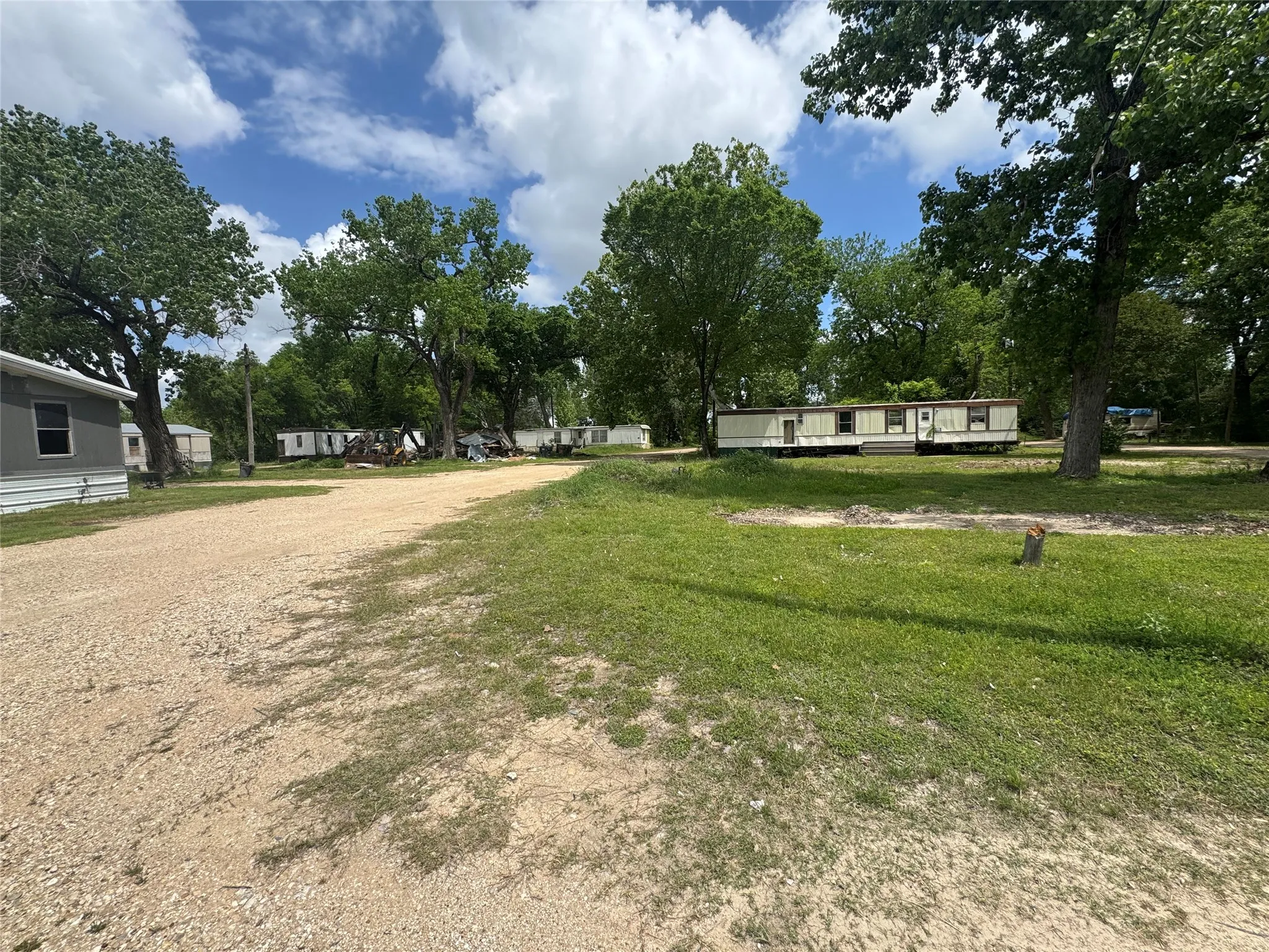 The property features a gravel pathway, surrounded by green grass and mature trees