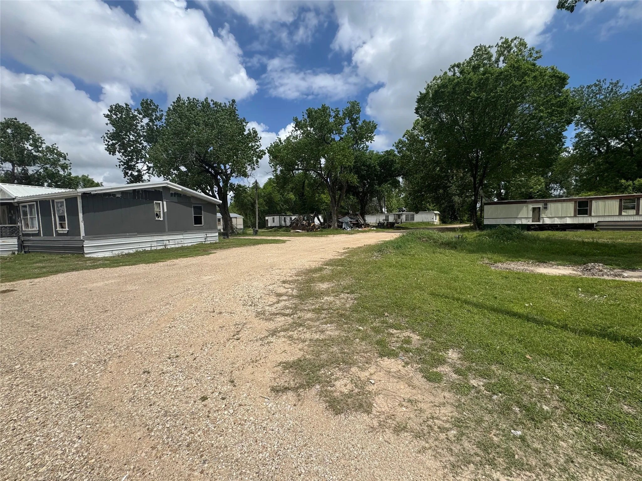 The property features a gravel pathway, green grassy areas, and mature trees