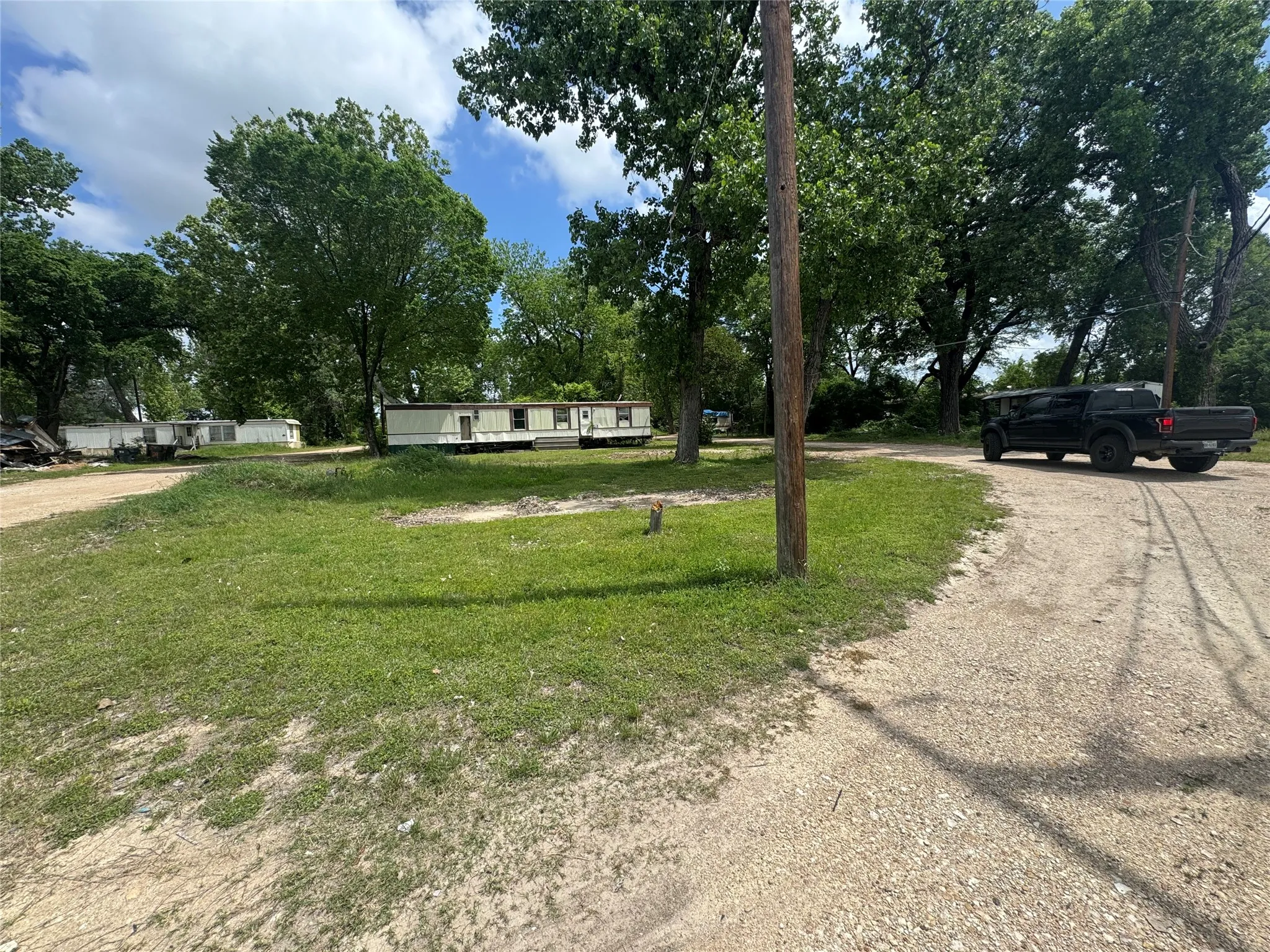 The property features a spacious lot with a gravel driveway and mature trees, providing a natural setting