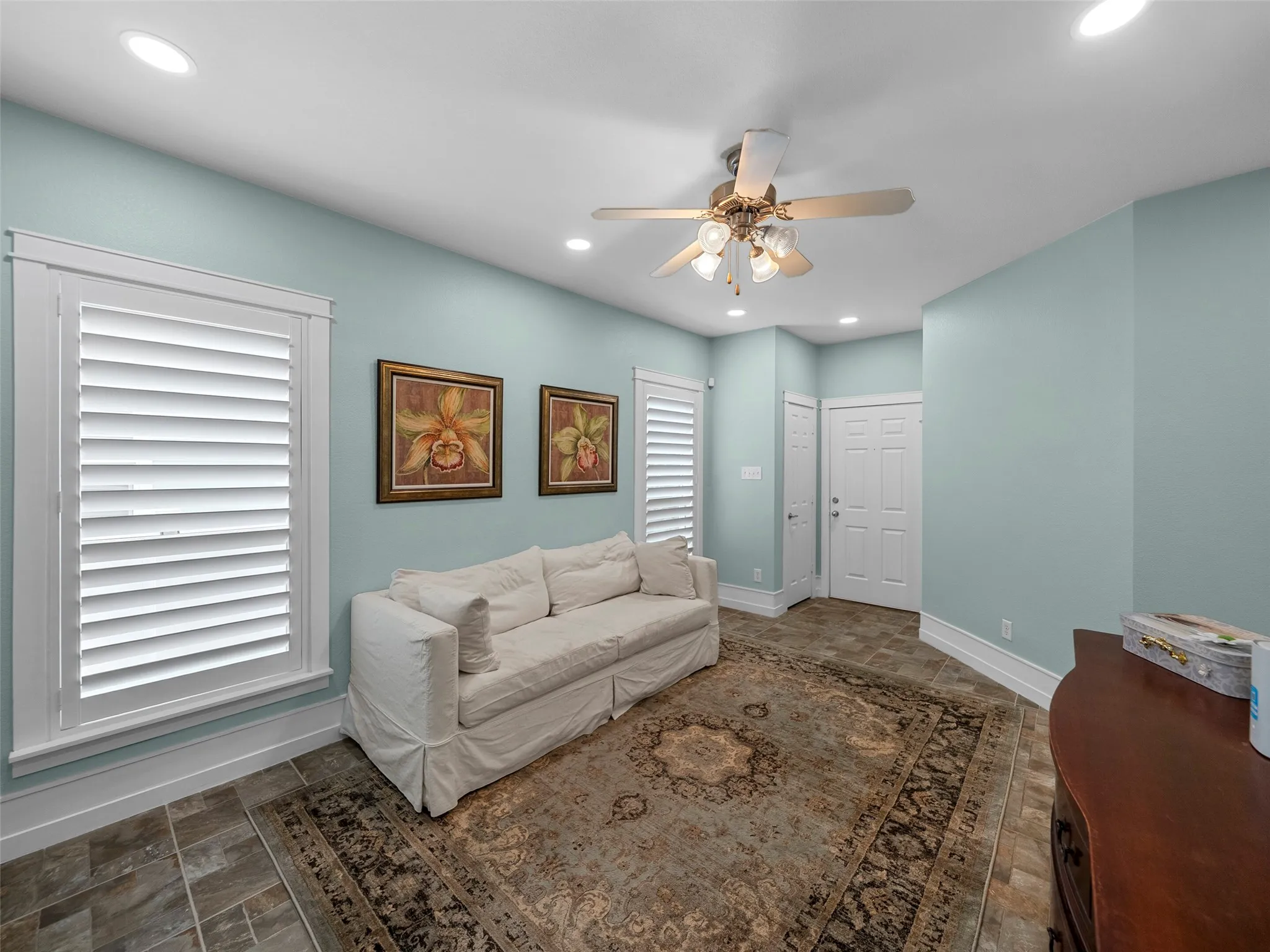 Living area with stone finish floors, a ceiling fan, and recessed lighting