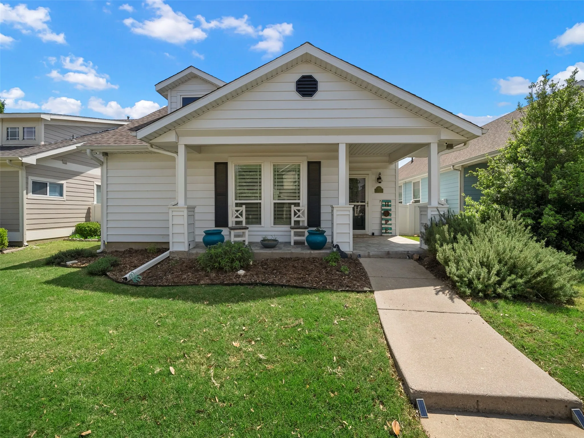 View of front of home with covered porch, a front lawn, and a shingled roof