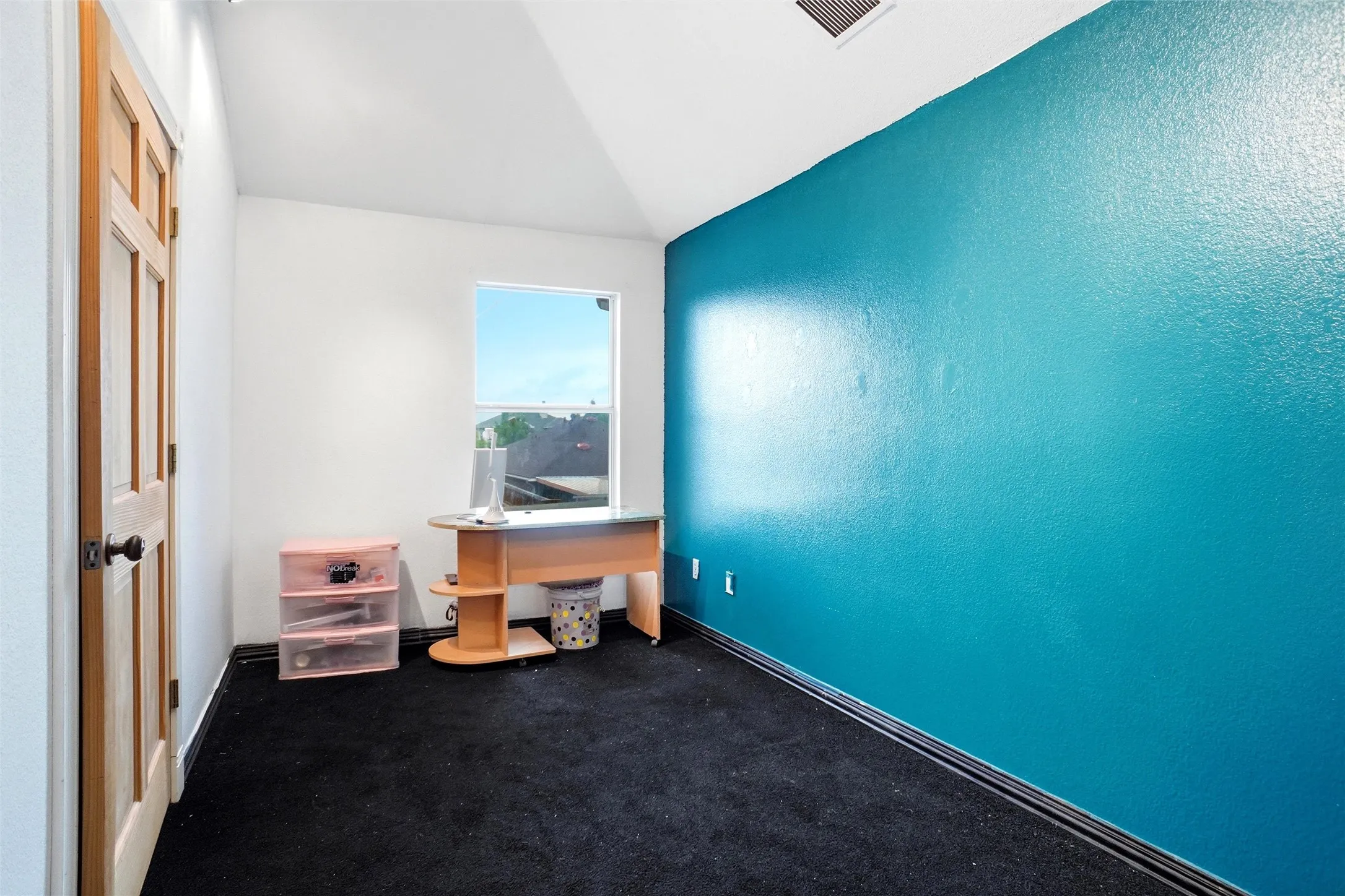 The room features a window providing natural light, a high vaulted ceiling, and contrasting wall colors