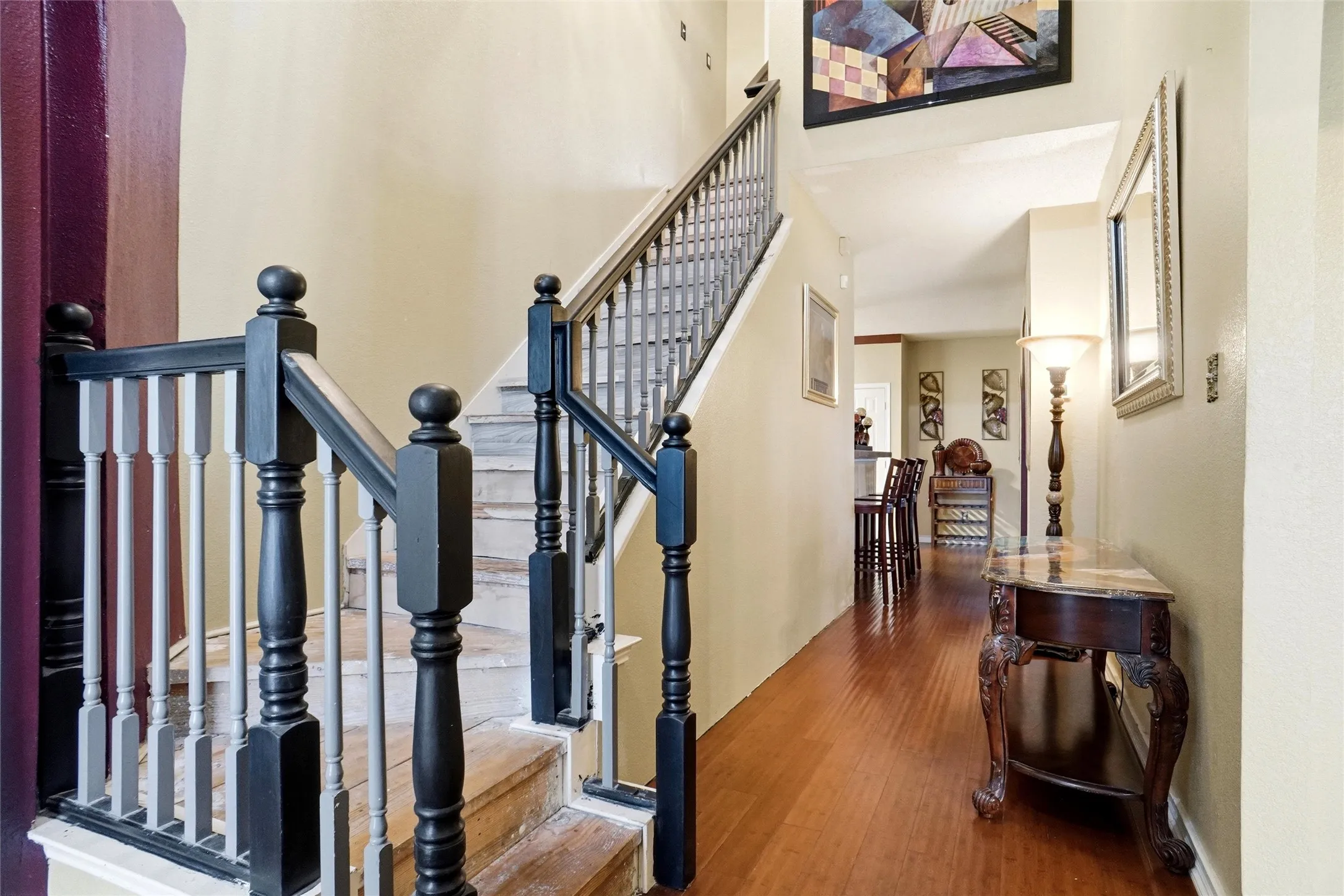 The property features a staircase with a black and gray banister, and a hallway with hardwood flooring
