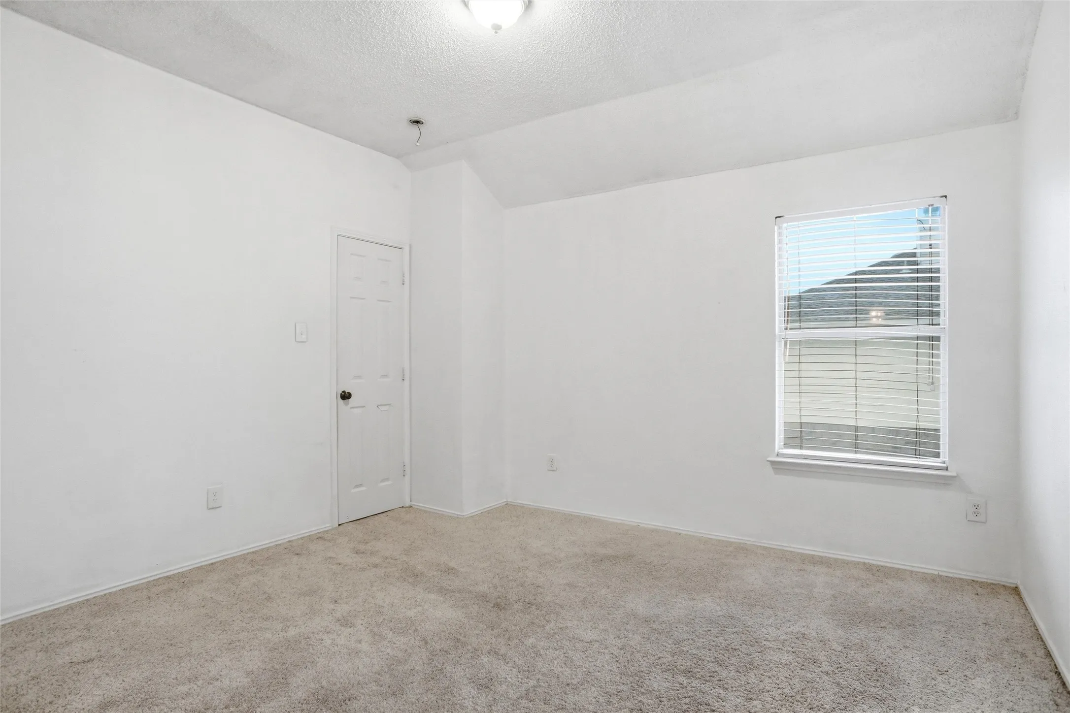 Room with neutral colored carpet flooring, white walls, and a window with blinds