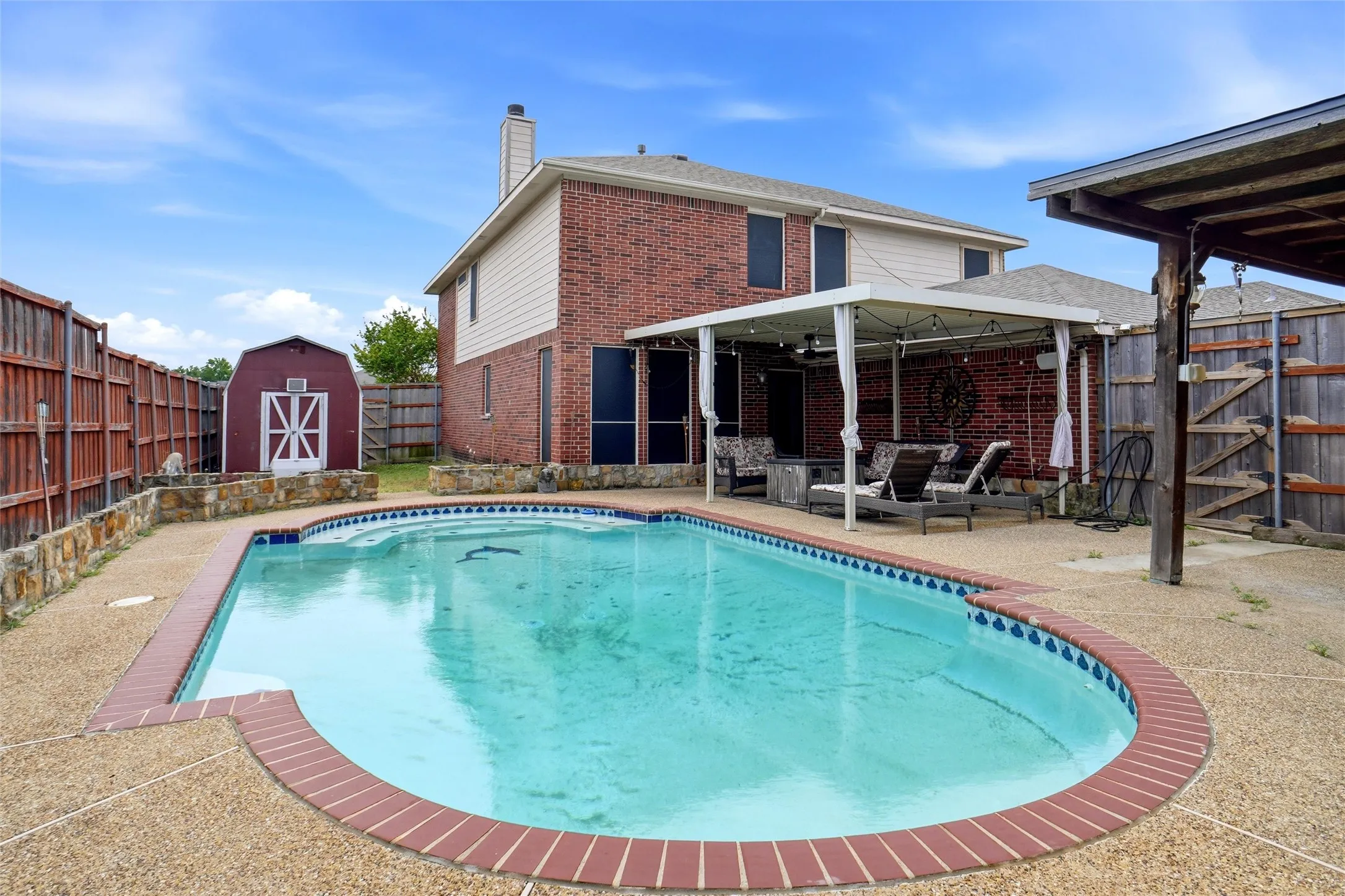 The property features a backyard swimming pool with a brick coping, a covered patio area, and a separate shed