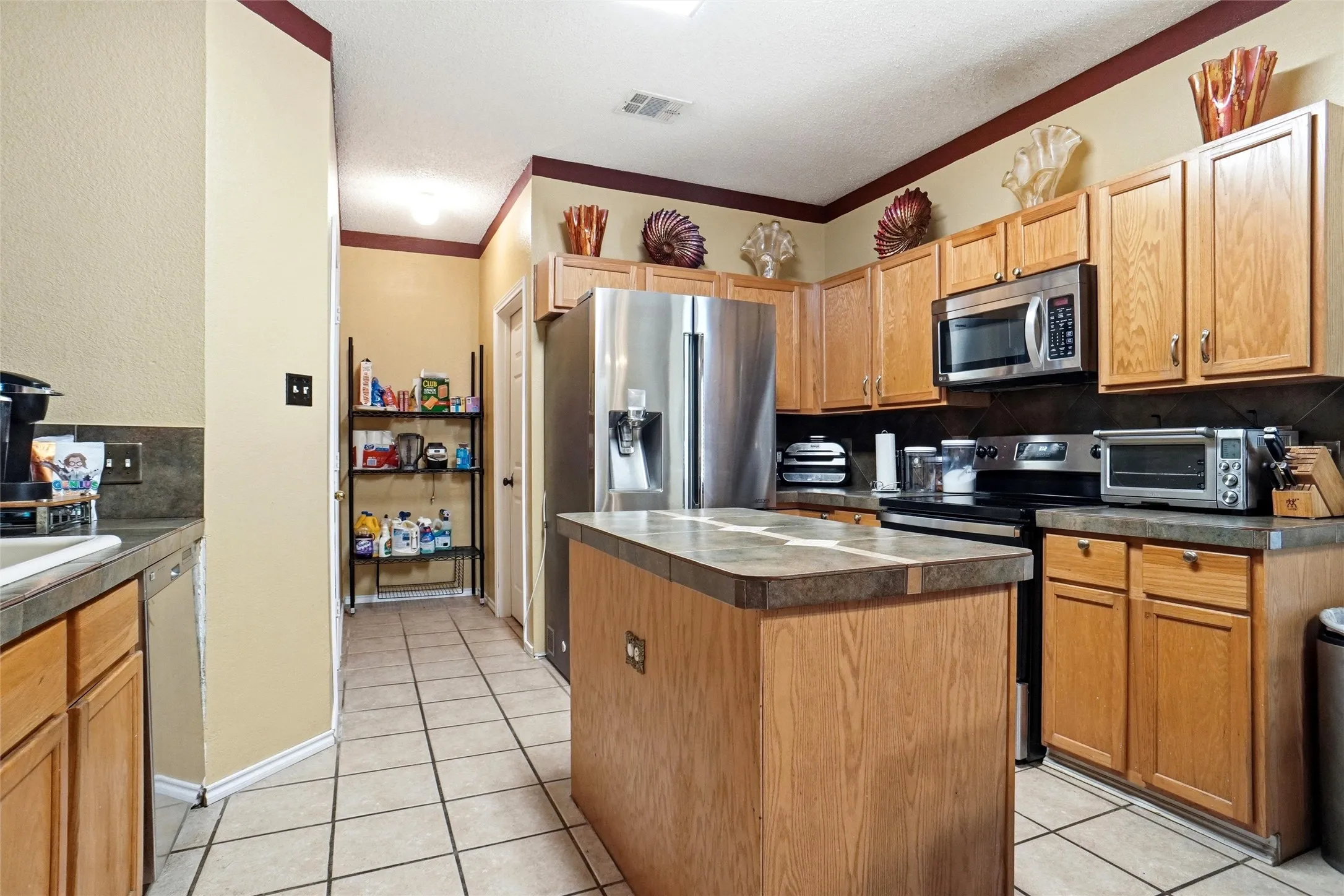 The kitchen features an island, stainless steel appliances, and wood cabinetry