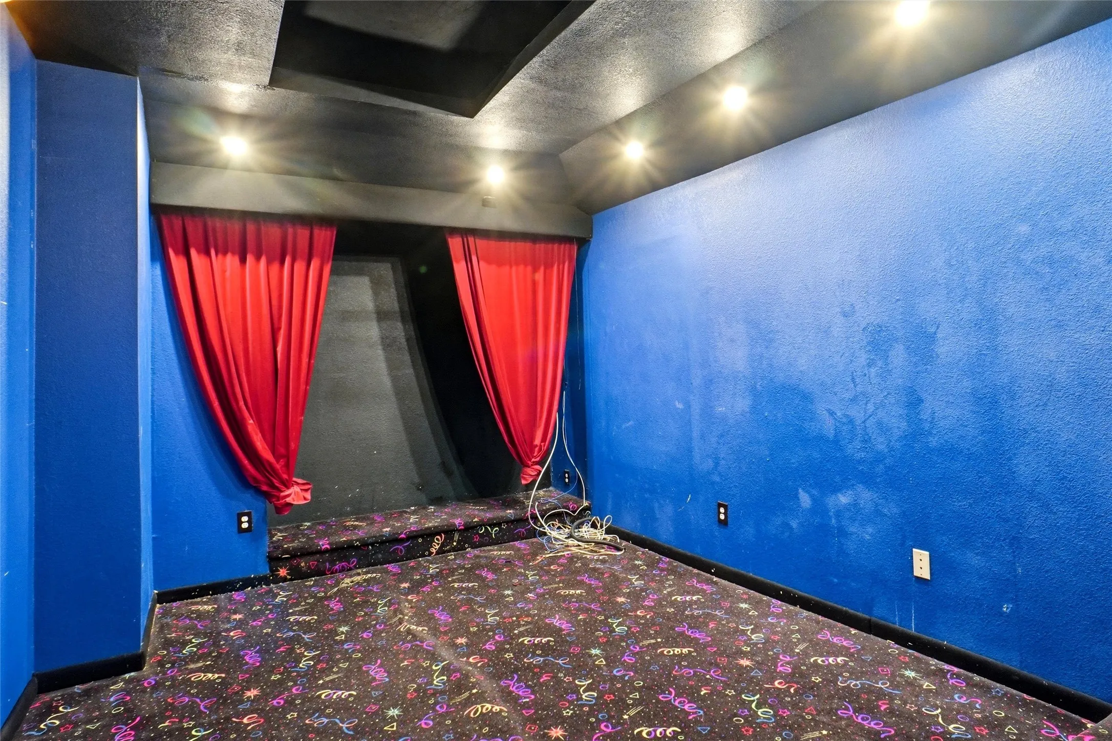 Recreation room featuring vibrant blue walls, track lighting, and a patterned carpet