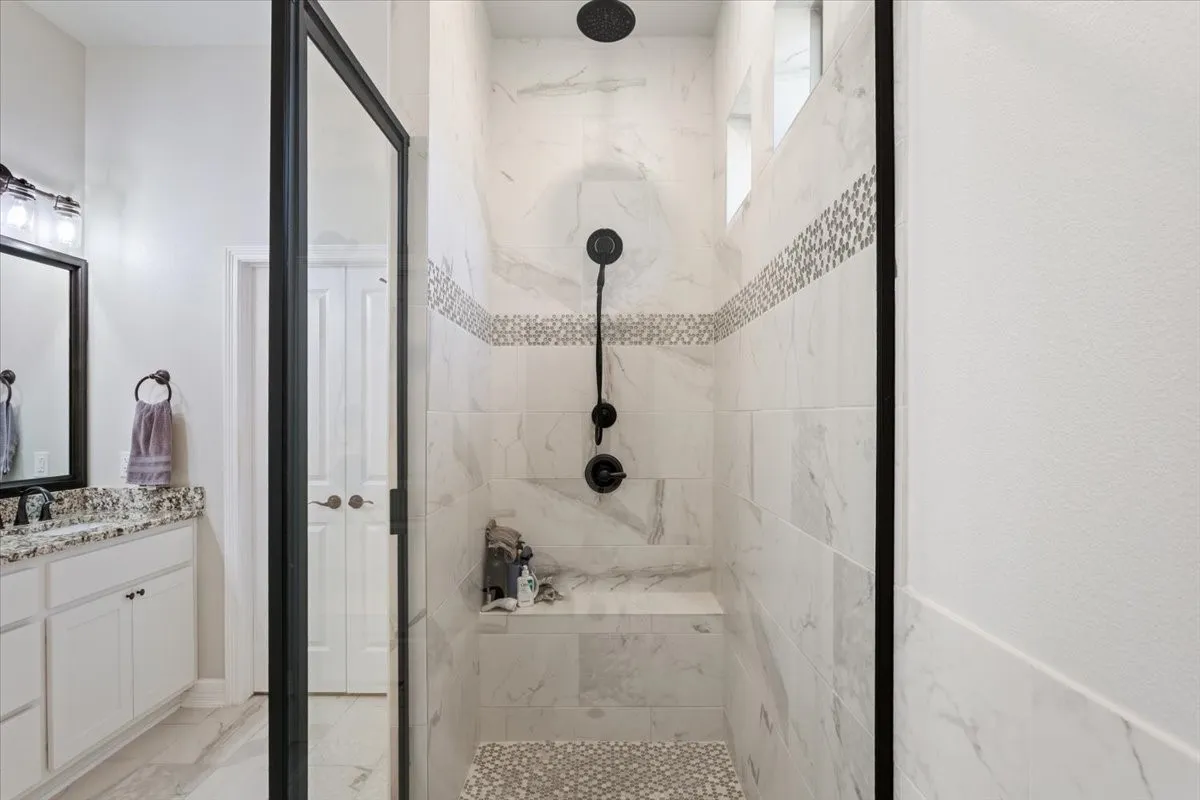 The bathroom features a spacious walk-in shower with tile walls, a decorative tile accent band, and a built-in bench