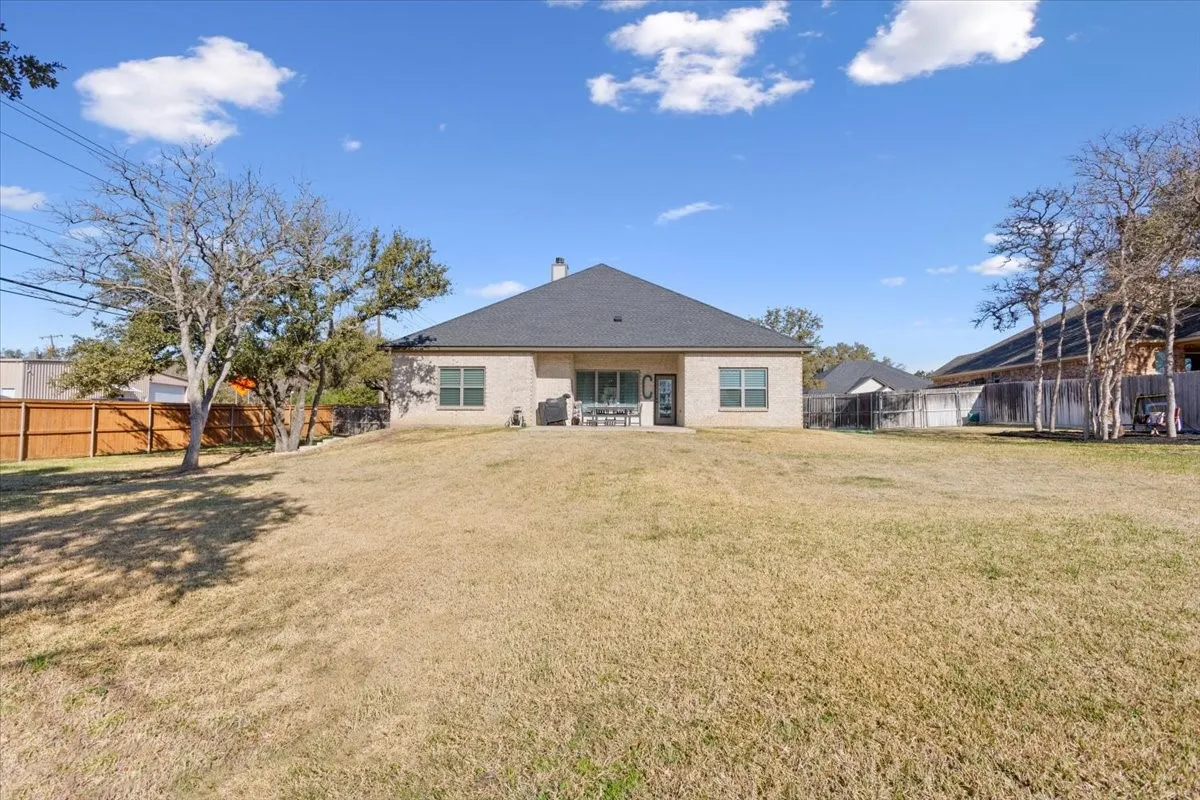 The property features a large yard with a lawn, a fenced perimeter, and mature trees