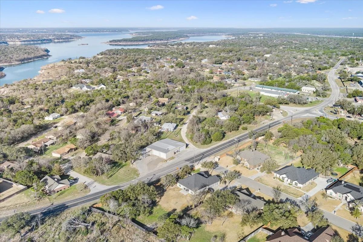 The property is situated in a community with extensive green spaces and trees, with a body of water visible in the background