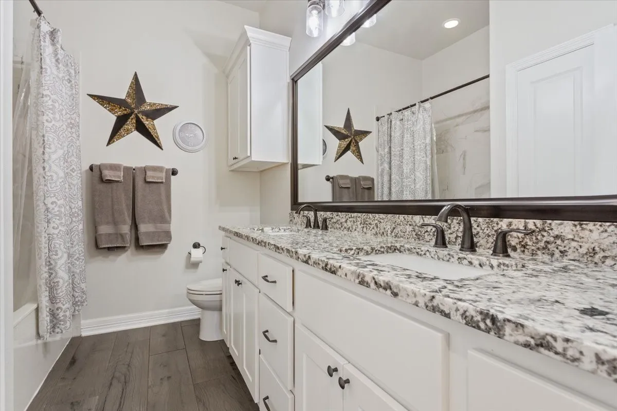 The bathroom features a double vanity with granite countertops, dark bronze faucets, and white cabinetry