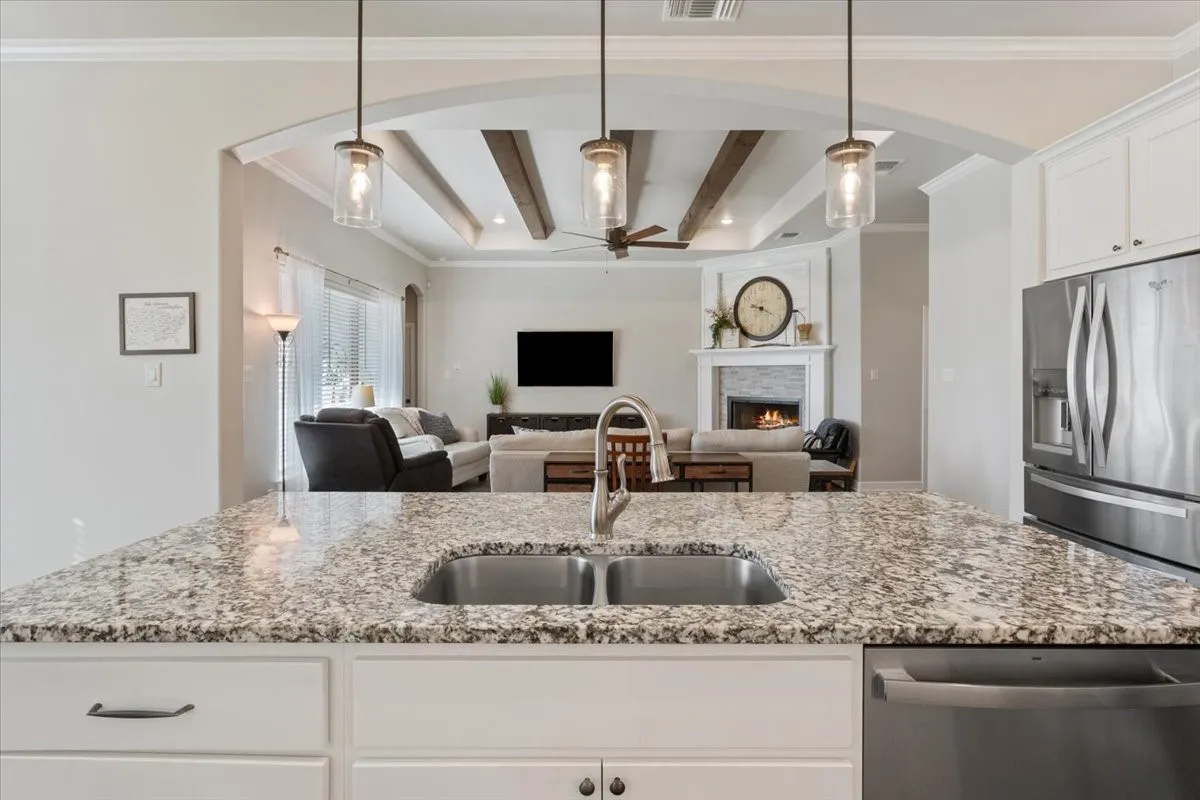 The kitchen features granite countertops with a stainless steel sink and a stainless steel refrigerator