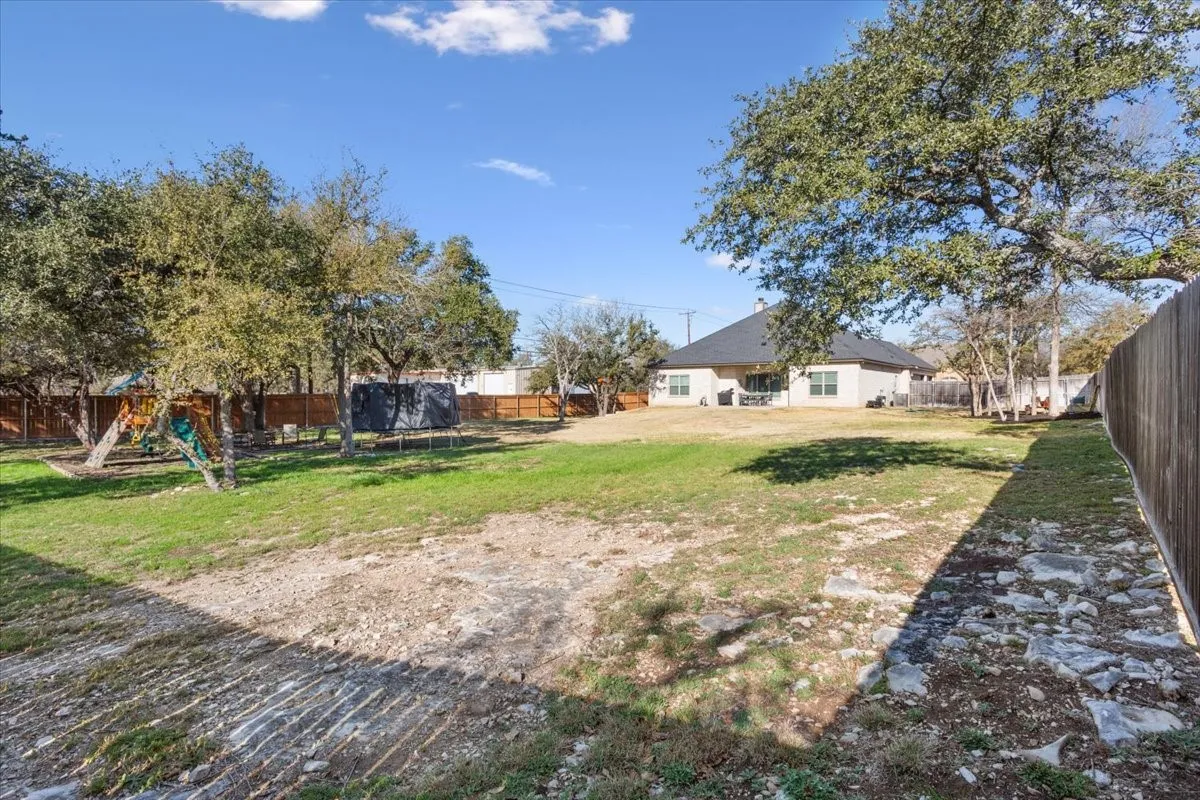 Expansive backyard featuring a partial fence, mature trees, and a view of the property's exterior