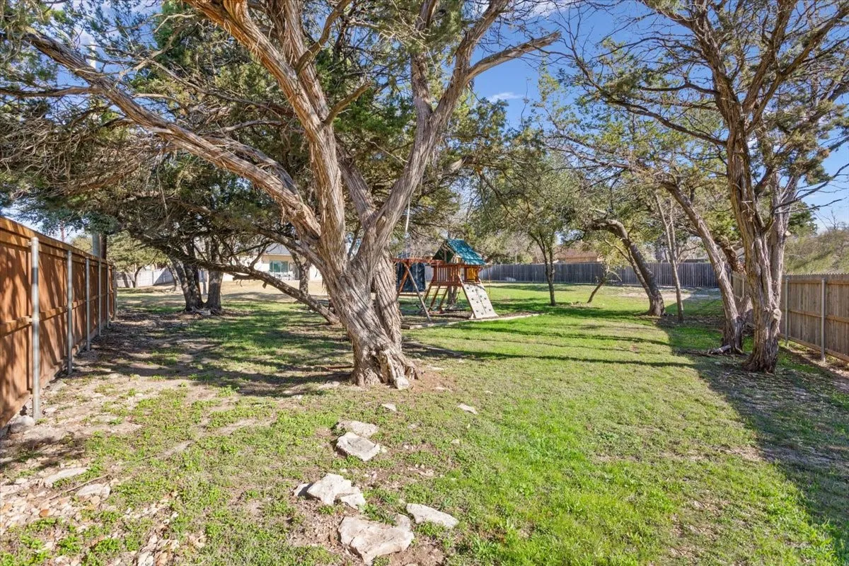 Expansive backyard featuring mature trees, a well-maintained lawn, and a privacy fence
