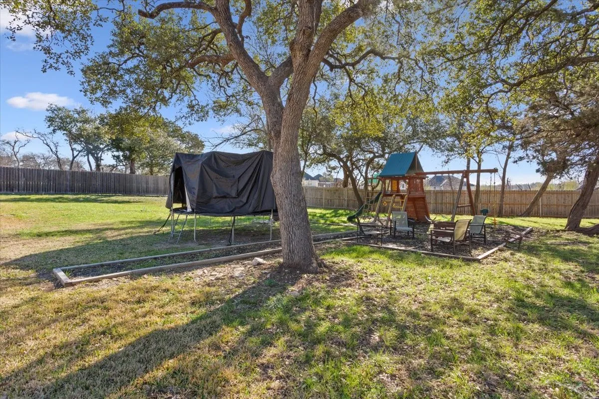 The property features an extensive yard with mature trees and a wooden privacy fence