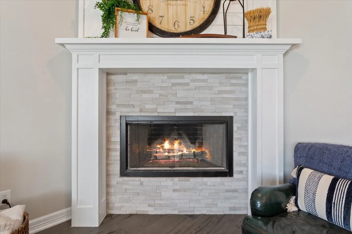 The property features a white wood fireplace surround with a light-colored stacked stone hearth and firebox