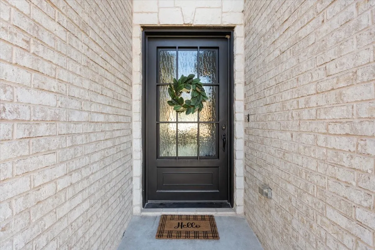 The property features an entryway with a dark-colored door, decorative glass inserts, and light-colored brick​​‌​​​​‌​​‌‌​‌‌​​​‌‌​‌​‌​‌​​​‌​​ siding