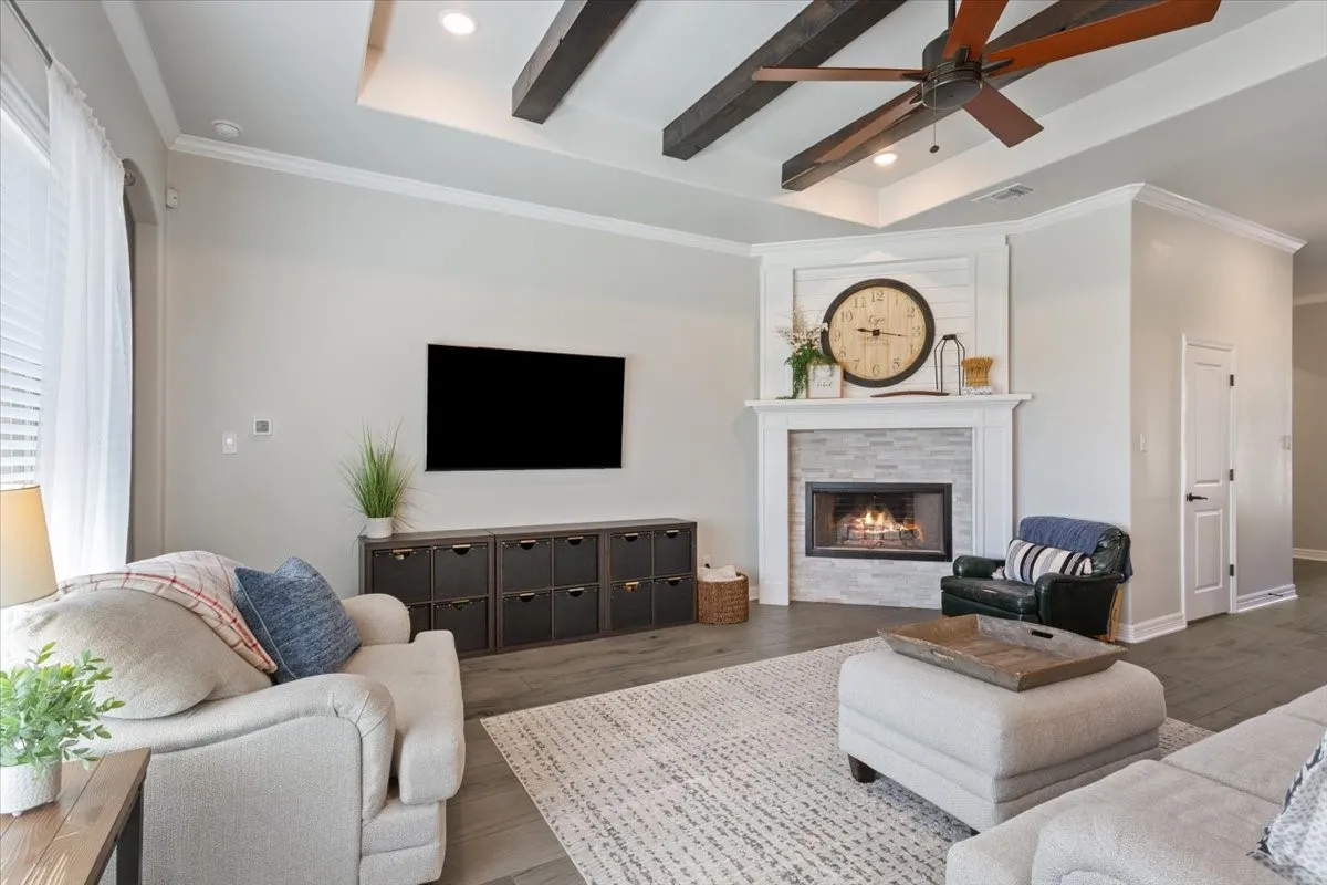The spacious living area features a decorative fireplace with a stone surround, a ceiling fan, and hardwood flooring