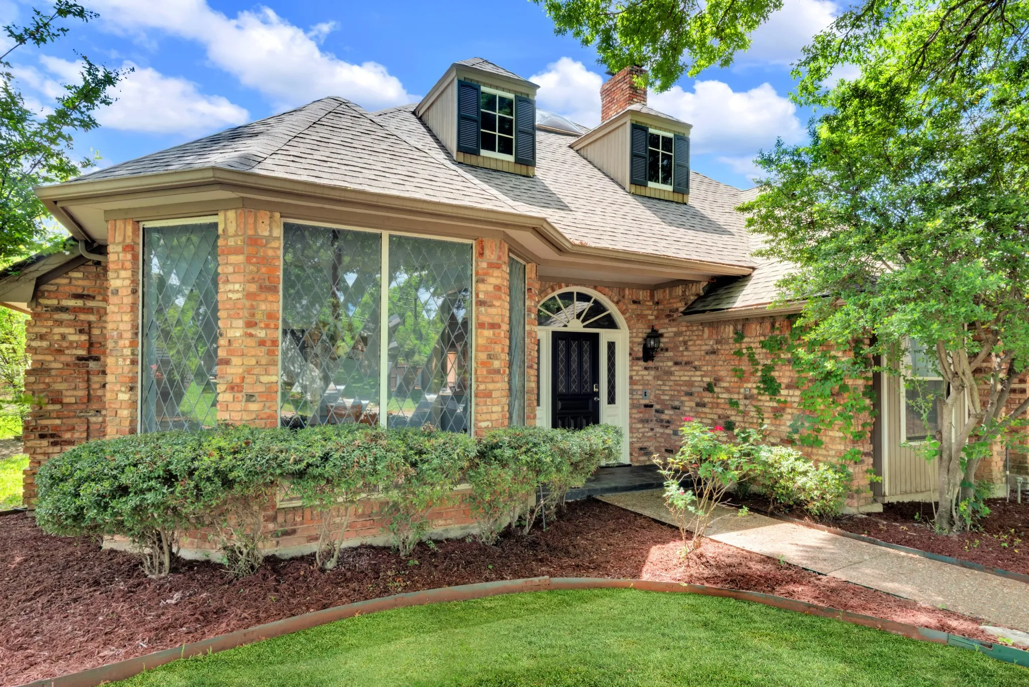 The property features a brick exterior, a bay window with decorative grilles, and a front entry with an arched transom window