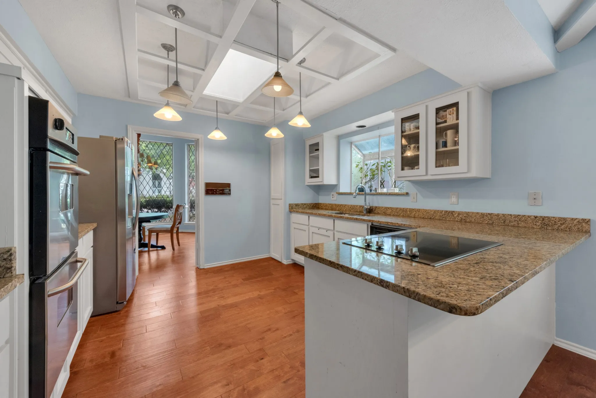 The kitchen features hardwood flooring, white cabinetry, and granite countertops