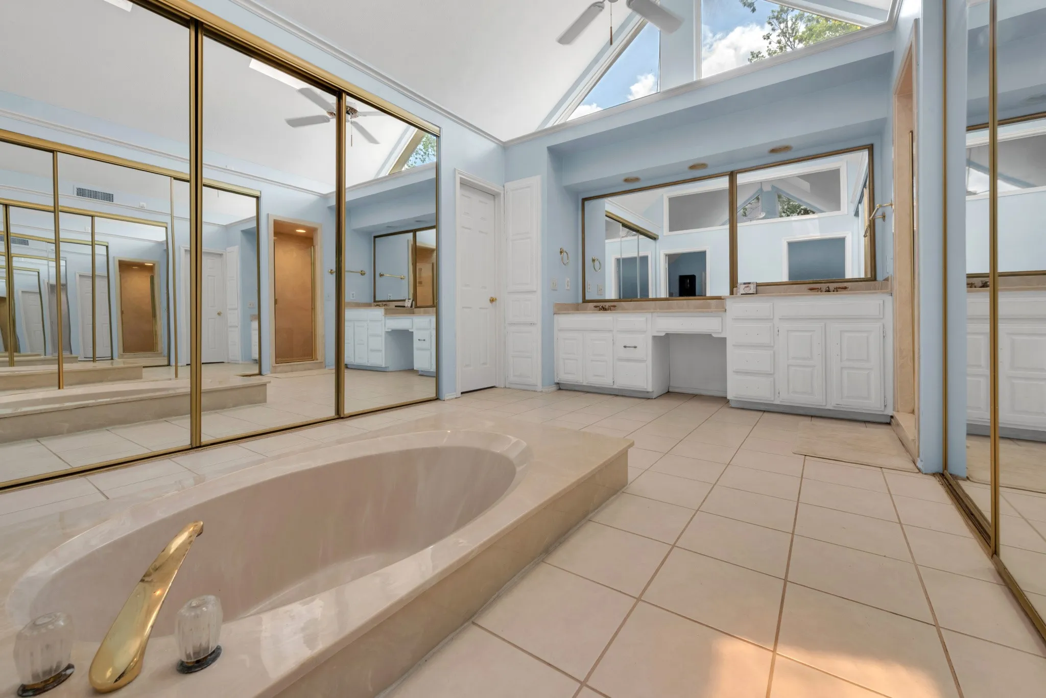 The bathroom features a built-in bathtub, tile flooring, and vaulted ceilings with expansive windows