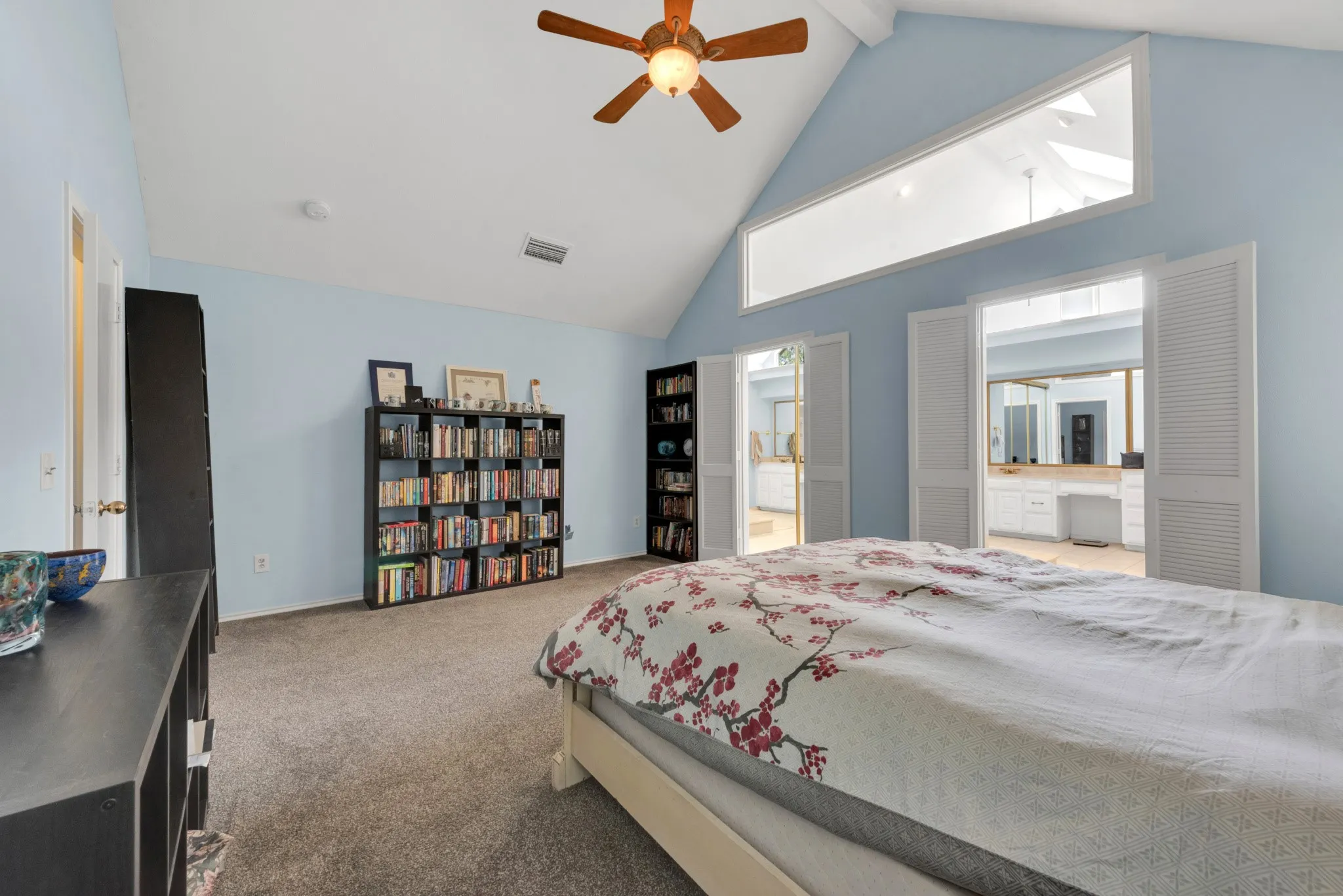 This room features a vaulted ceiling with a ceiling fan and a high rectangular window