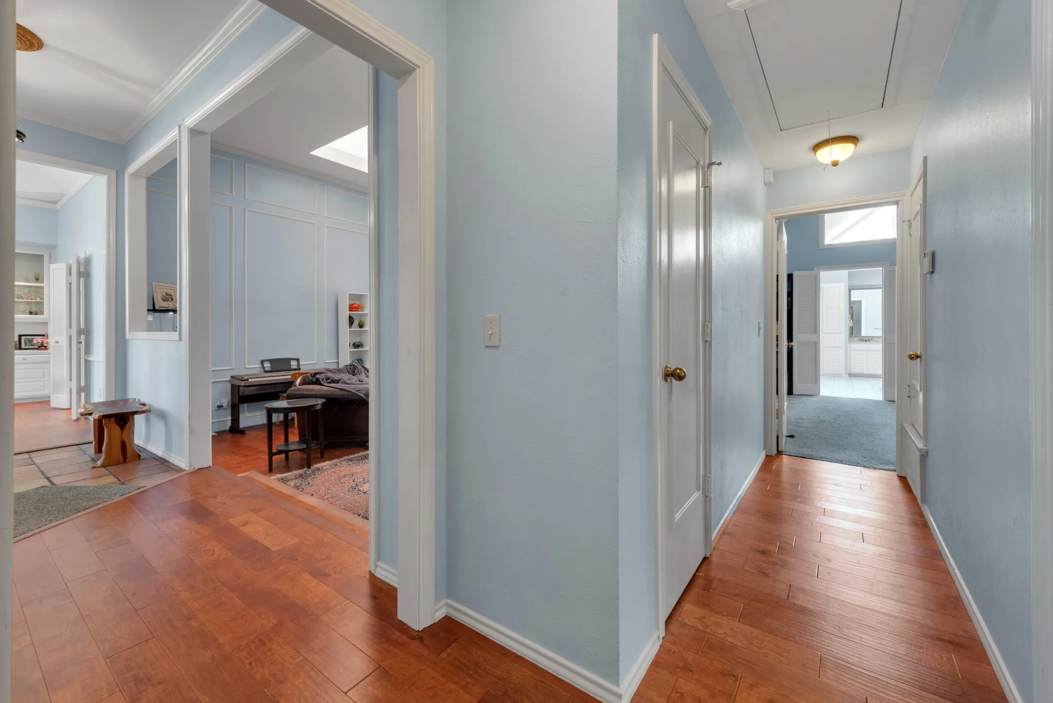 Hallway featuring wood flooring, light blue walls, and white trim