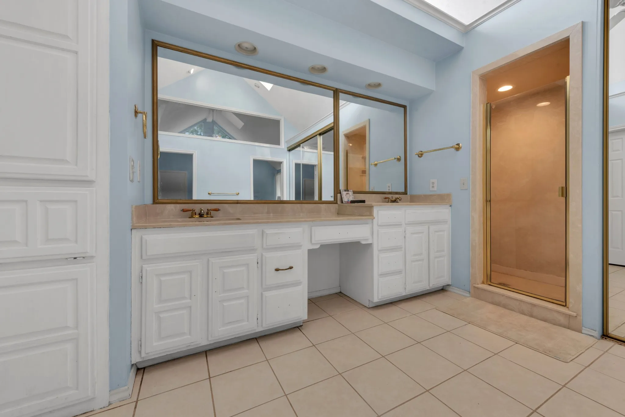 Bathroom featuring a large vanity with two sinks, a separate shower, and tiled flooring
