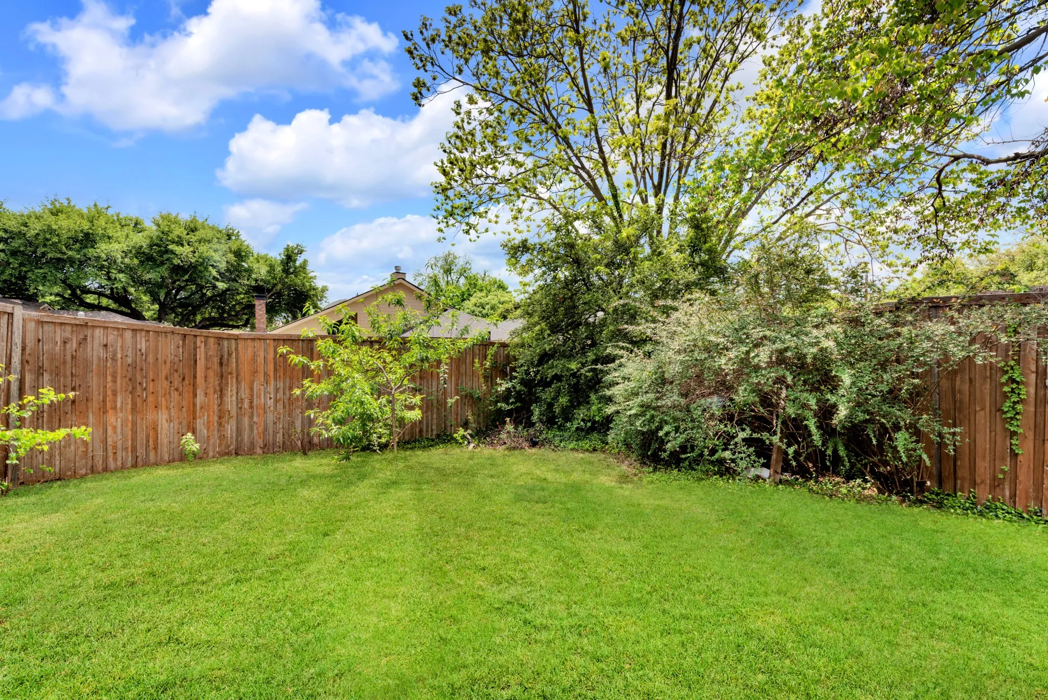 The property features a spacious lawn with a wooden fence and mature trees