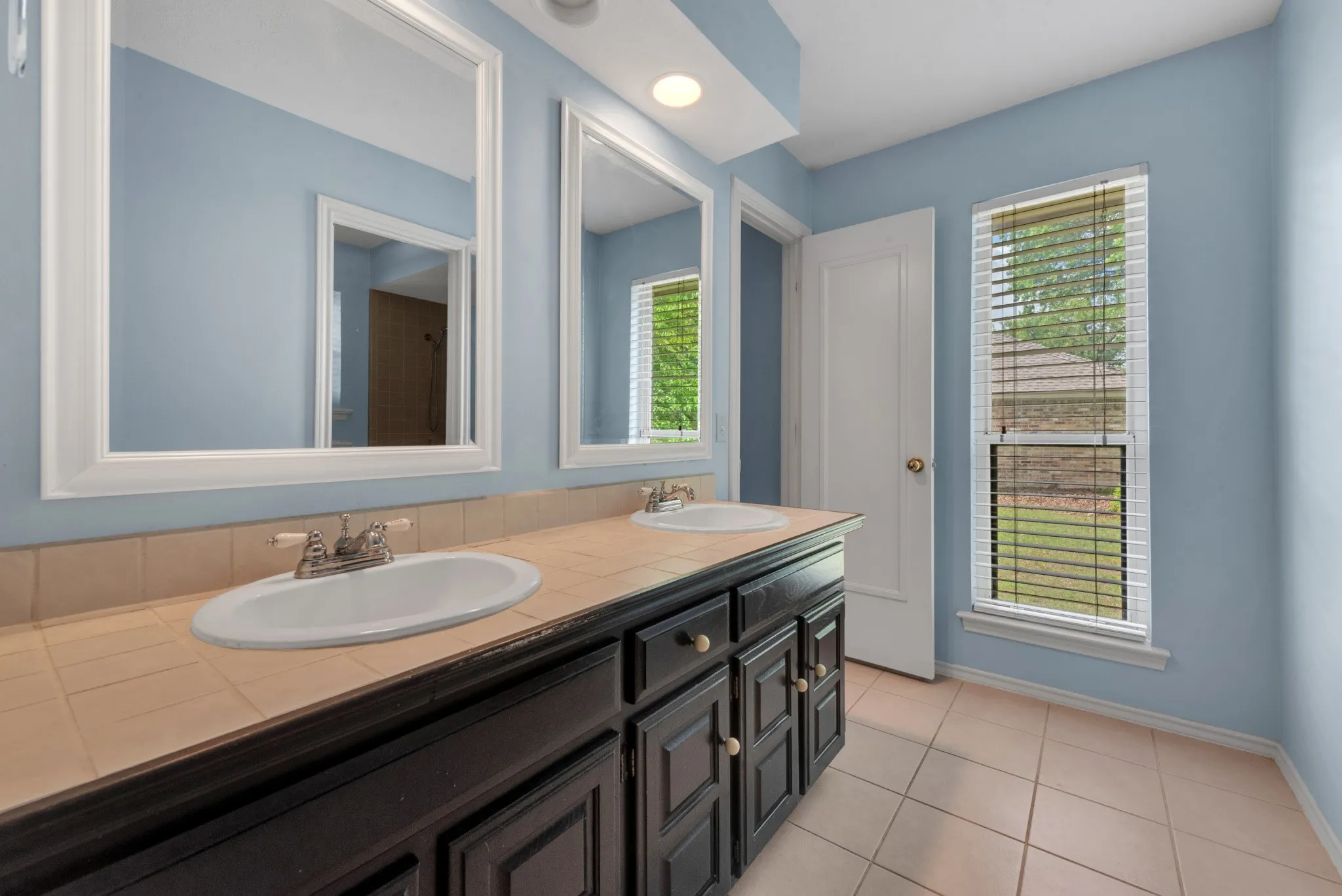 Bathroom featuring a double vanity with two sinks, two framed mirrors, and tile flooring