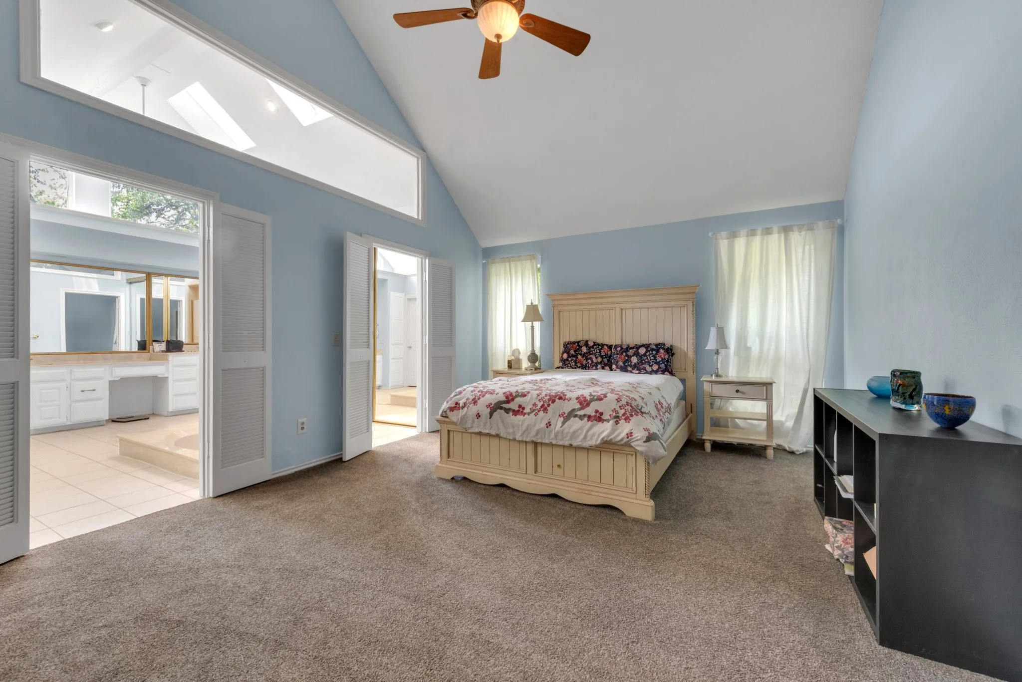 Spacious room with a vaulted ceiling, a ceiling fan, and carpeted flooring
