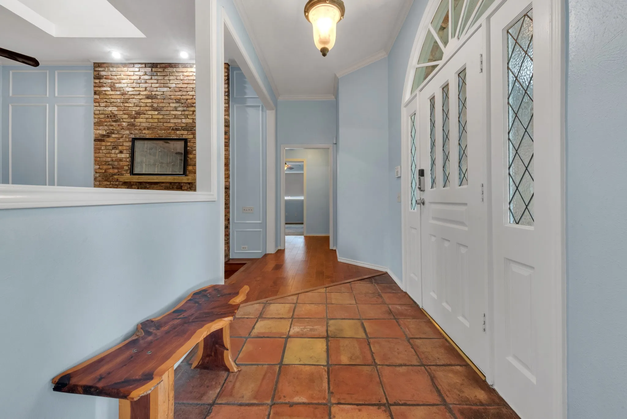 Entryway featuring terracotta tile flooring, a decorative white front door with leaded glass panels, and a prominent pendant light fixture