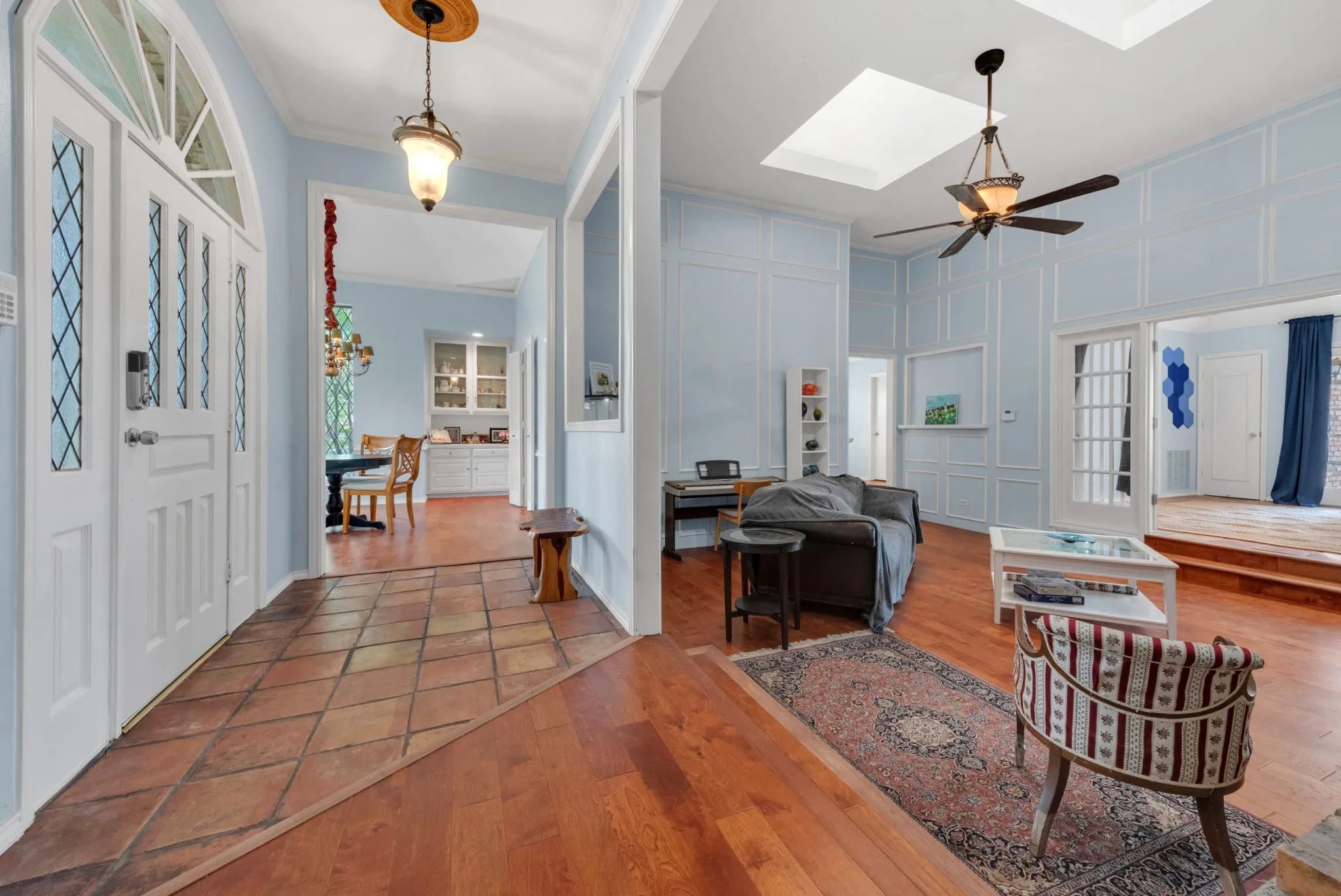 The property features a spacious entry with tile flooring, leading to a living area with hardwood floors, a skylight, and a ceiling fan