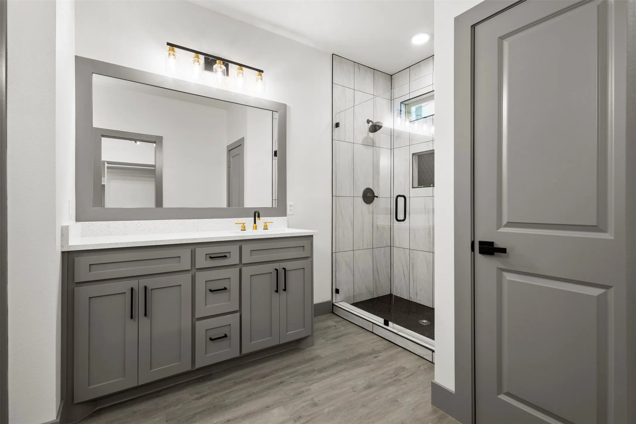 Bathroom featuring a spacious vanity with gray cabinetry, a white countertop, and a large mirror