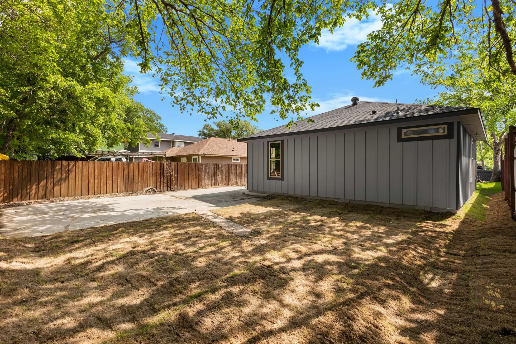 The property features a fenced yard with a concrete driveway and mature trees