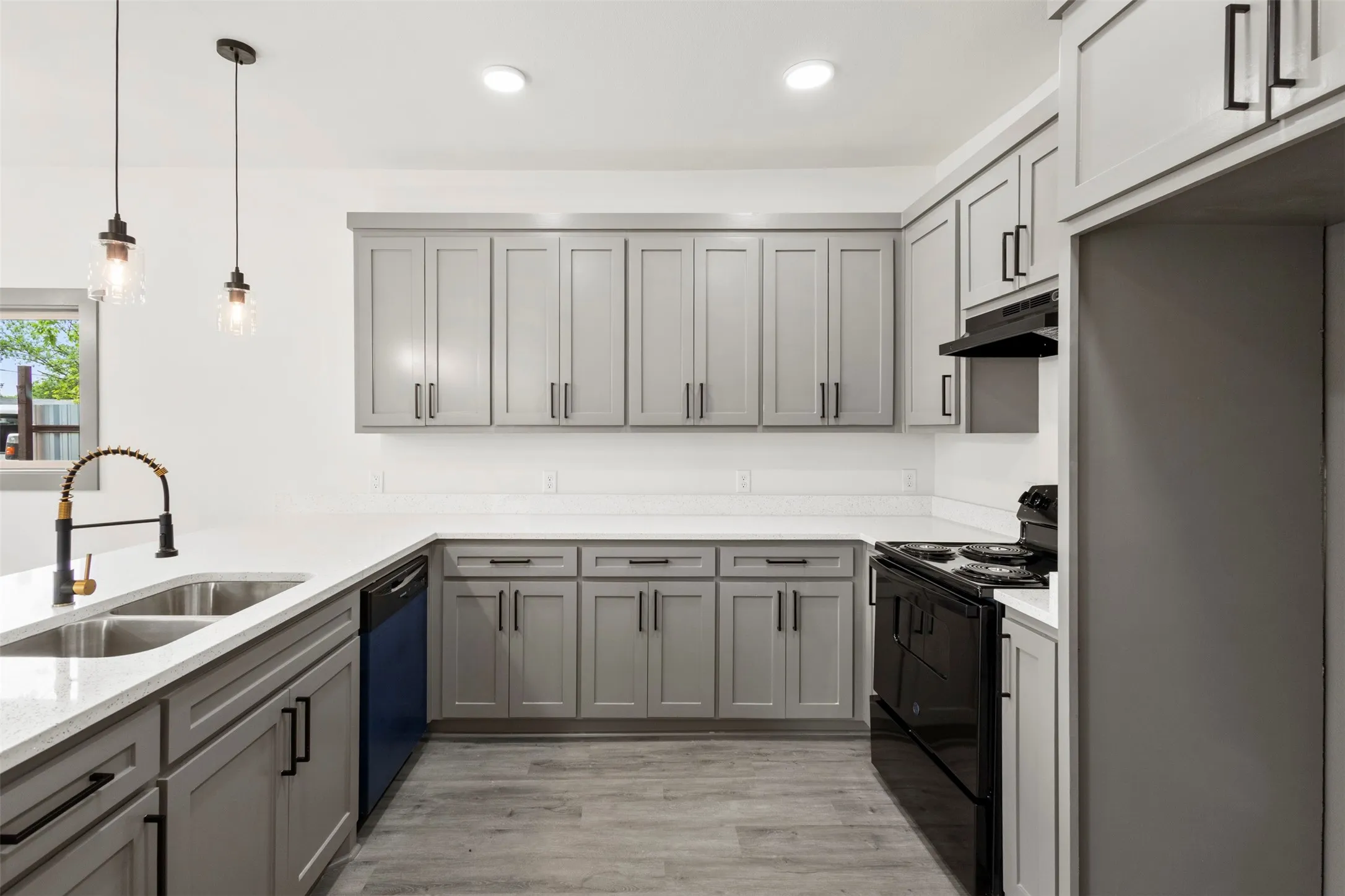 The kitchen features grey cabinetry with black hardware, white countertops, and a double basin sink with a black faucet