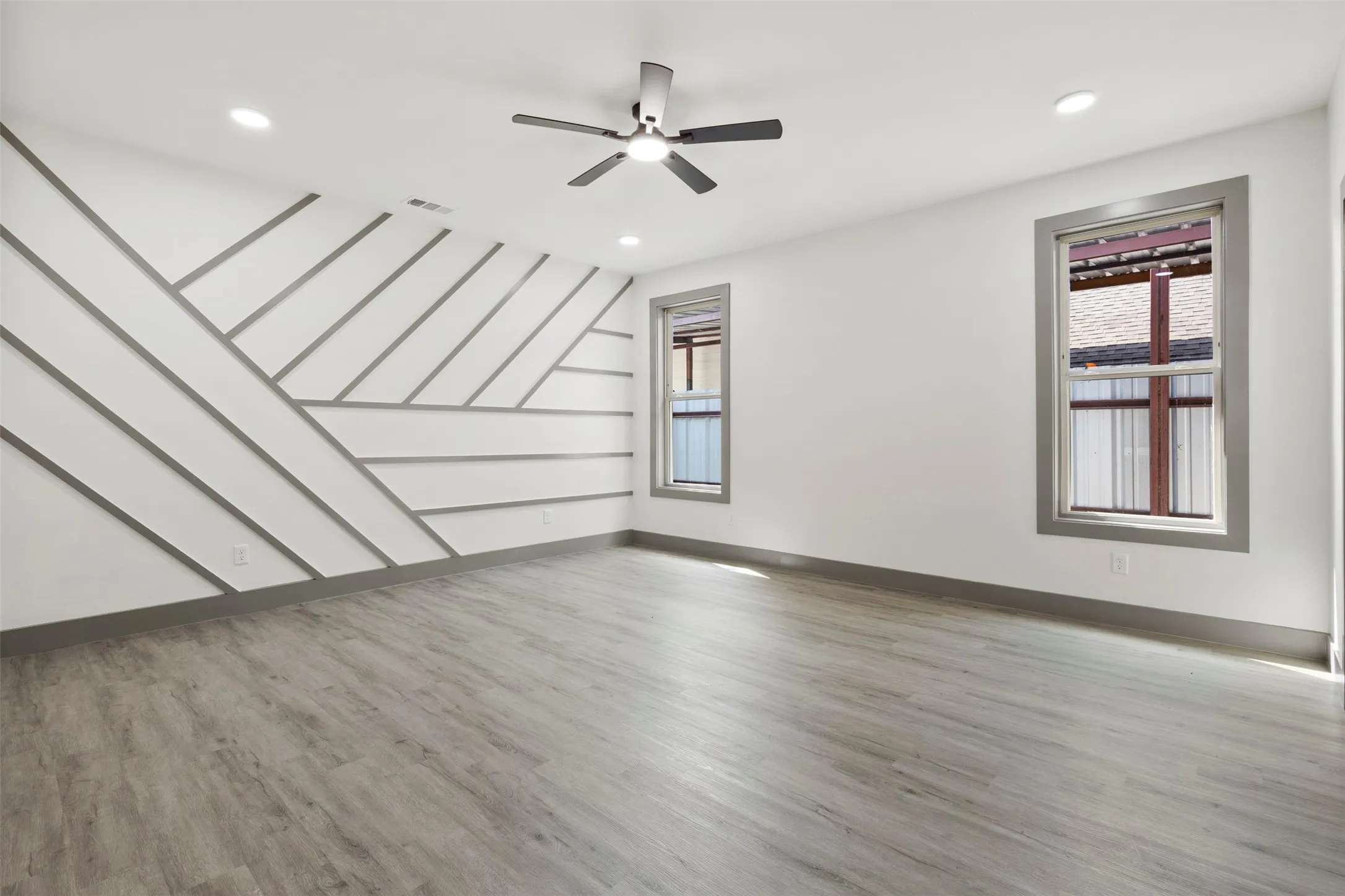 Spacious room featuring light-colored flooring, recessed lighting, and a ceiling fan