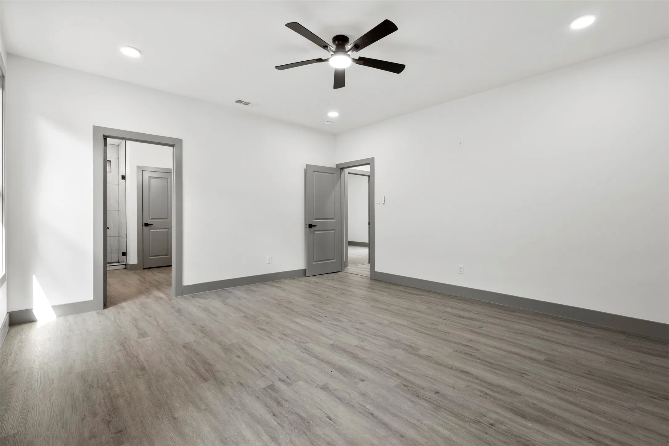 Spacious room featuring light-colored flooring, white walls, and recessed lighting