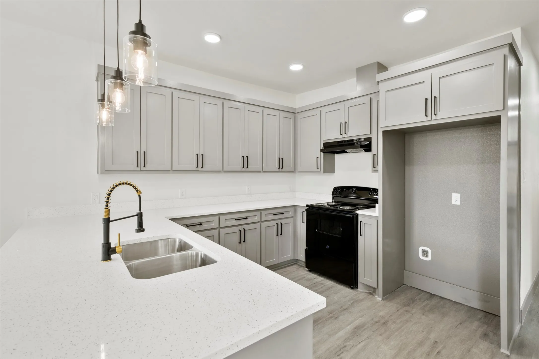 The kitchen features sleek grey cabinetry, white countertops, and a double basin stainless steel sink with a modern black and gold faucet