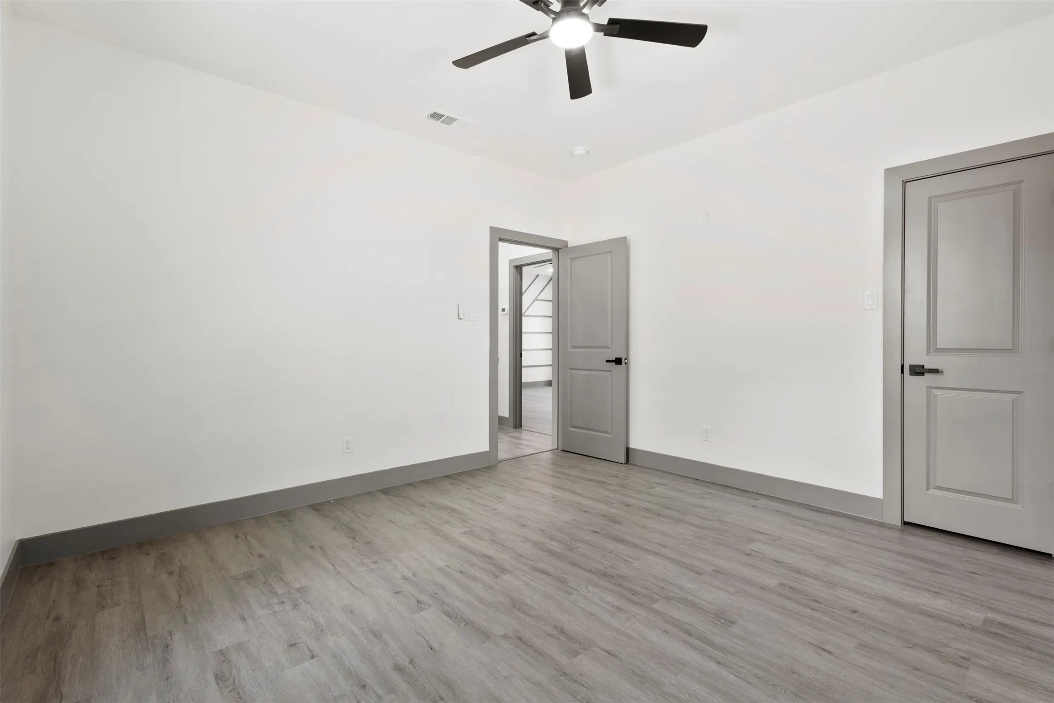 This room features light-colored flooring, white walls, and a ceiling fan with integrated lighting