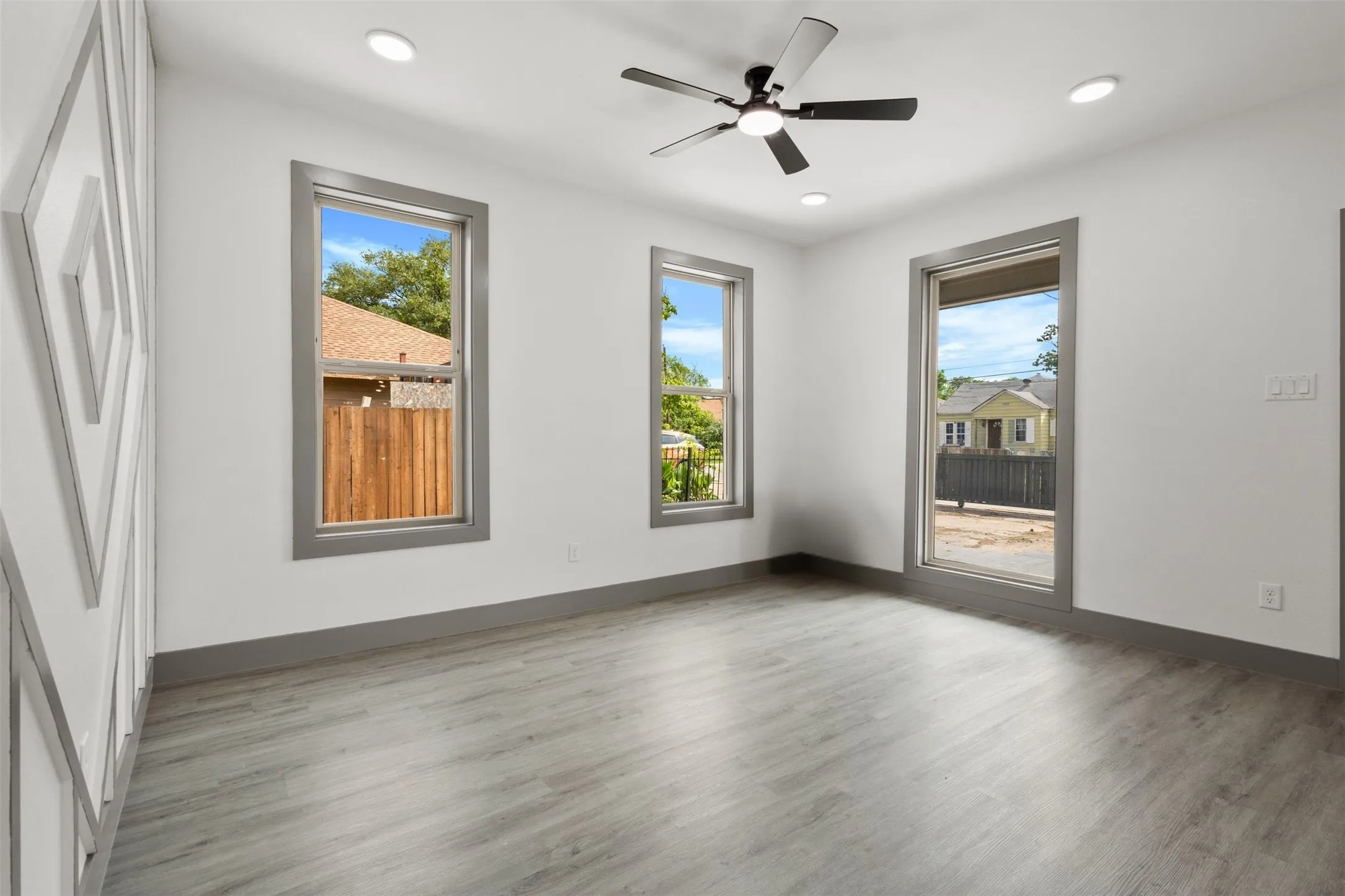 This room features light-colored flooring, white walls, and three windows with gray trim
