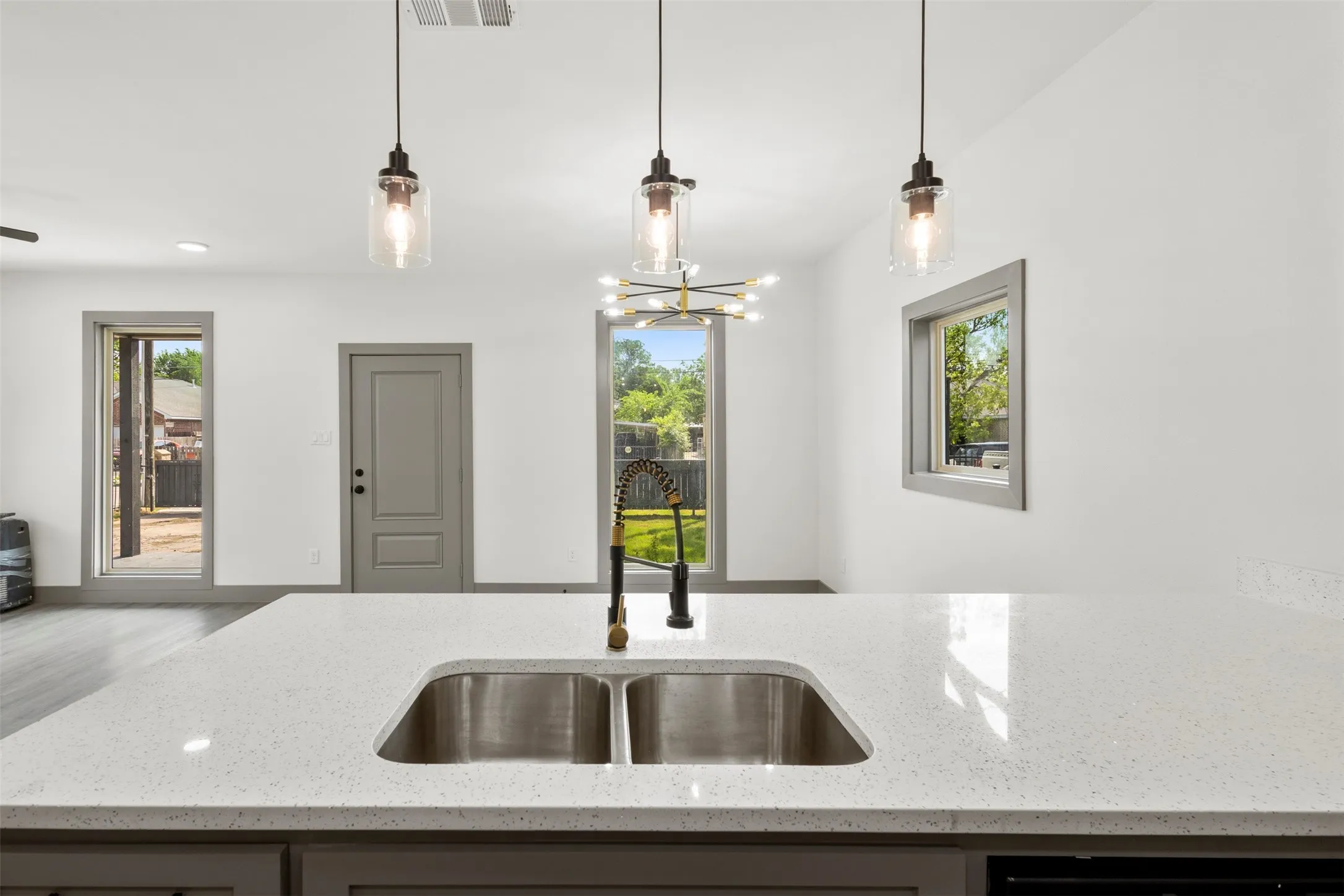 The kitchen features a spacious island with a double stainless steel sink and a contemporary pull-down faucet
