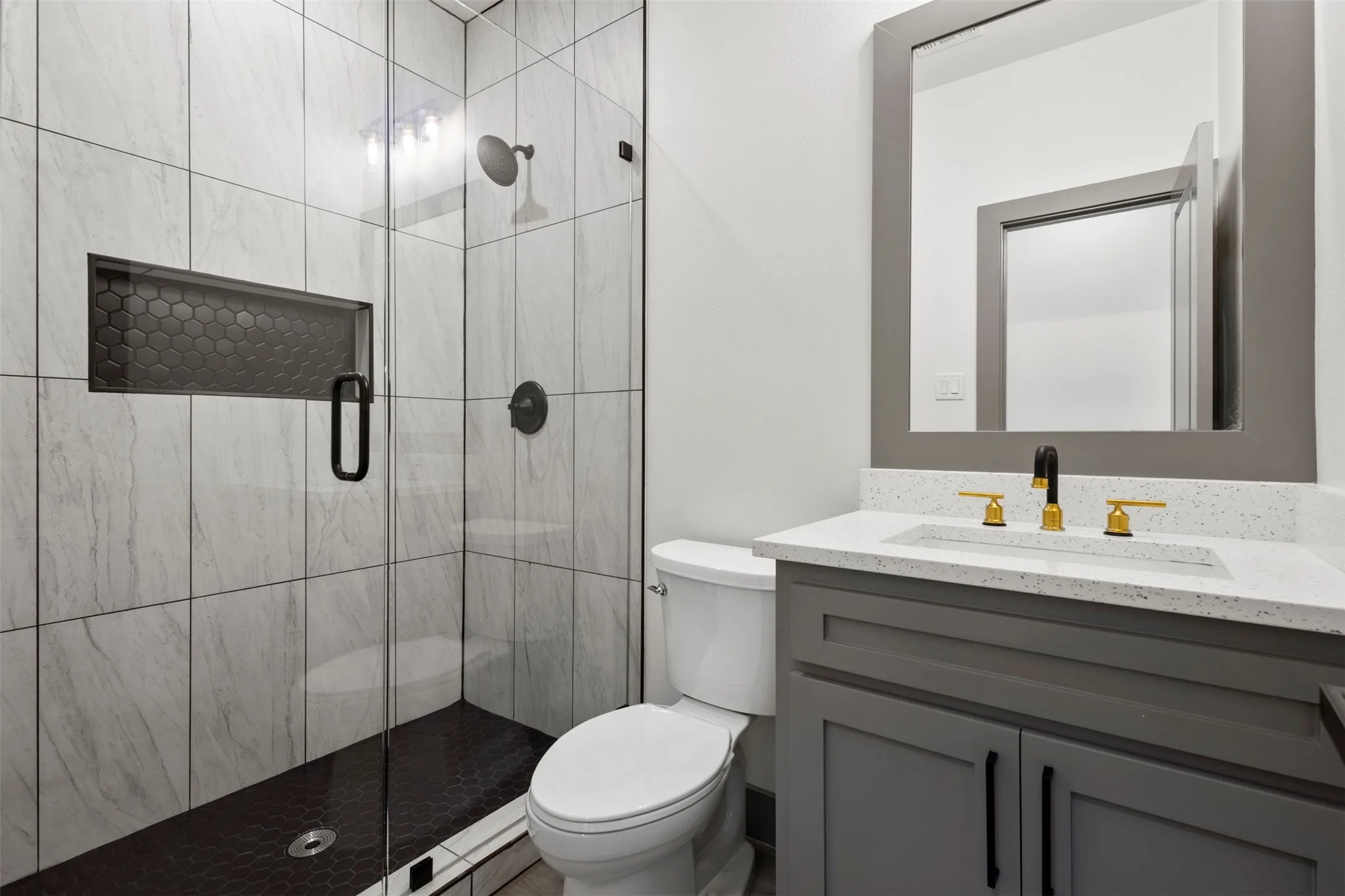 Bathroom featuring a glass-enclosed shower with tiled walls and a dark hexagonal tiled floor