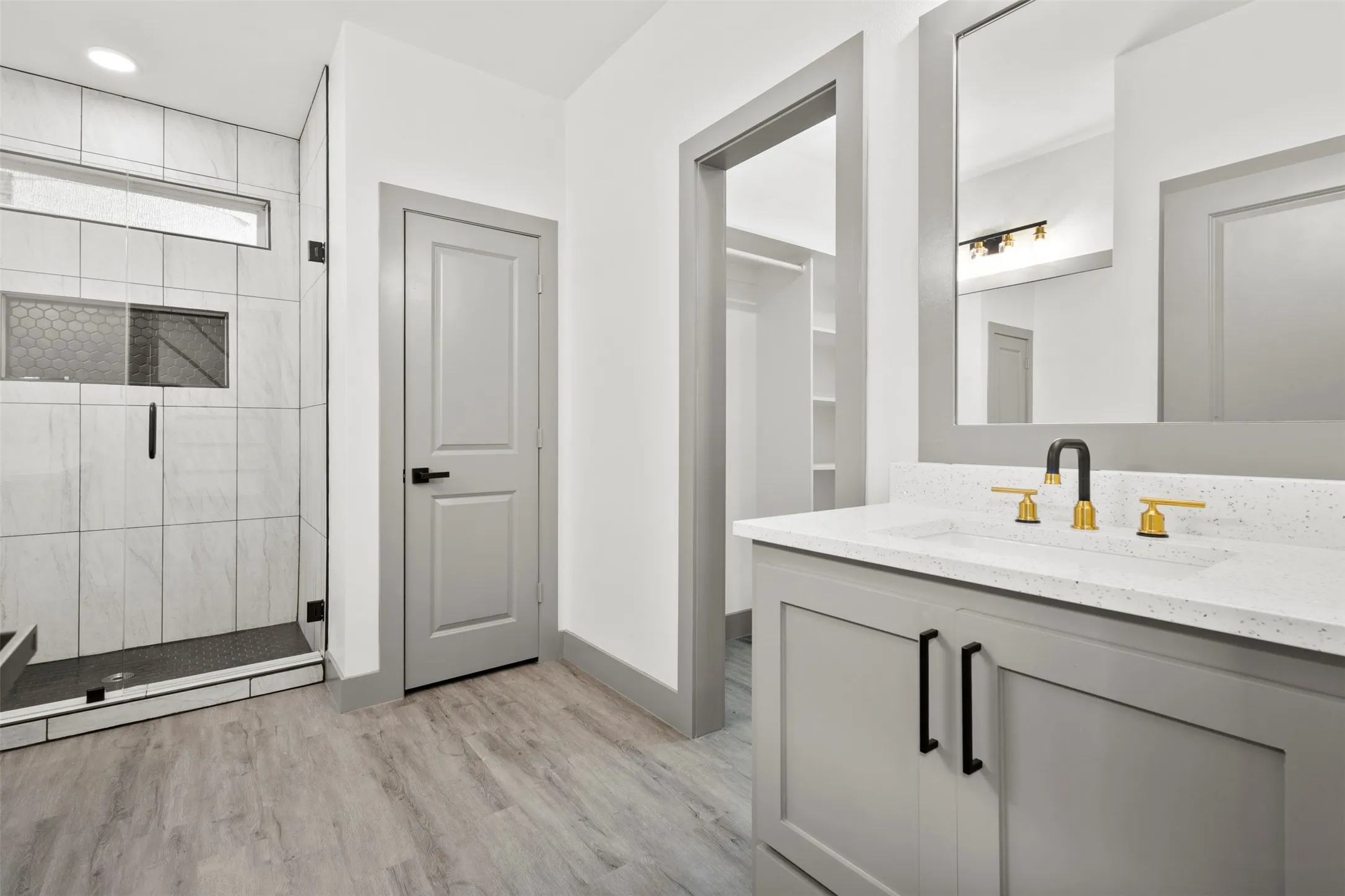 This bathroom features a contemporary vanity with a white countertop and a black and gold faucet