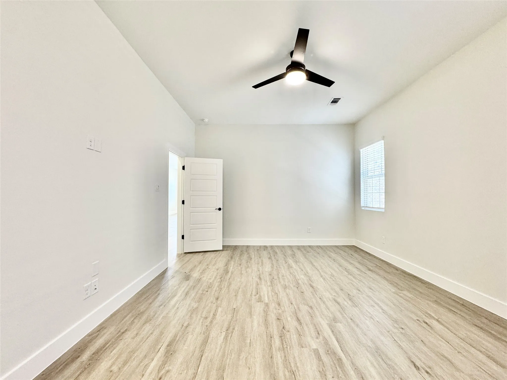 Spare room with wood finished floors, a ceiling fan, and baseboards