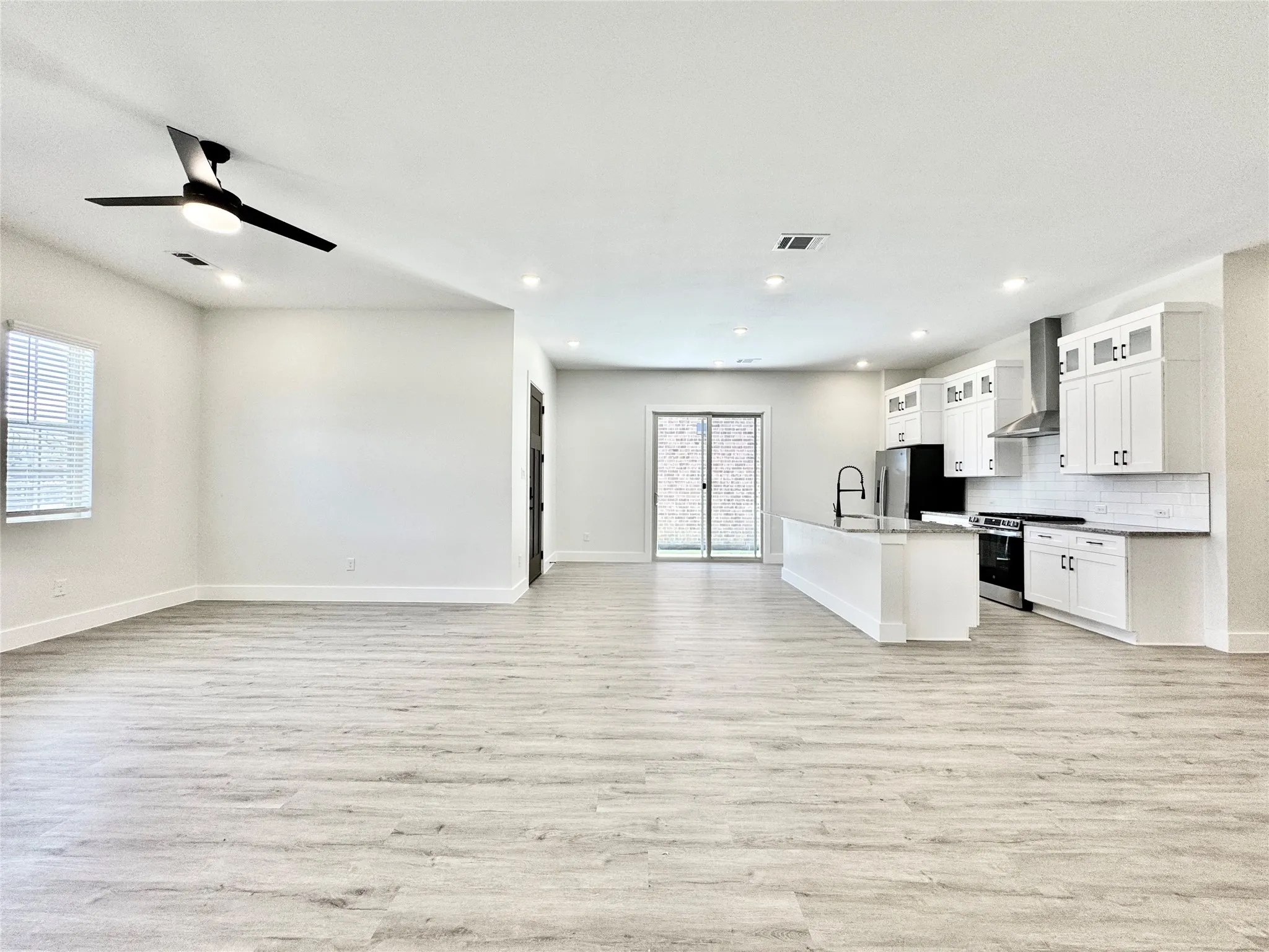 Unfurnished living room featuring a sink, light wood-style floors, baseboards, ceiling fan, and recessed lighting